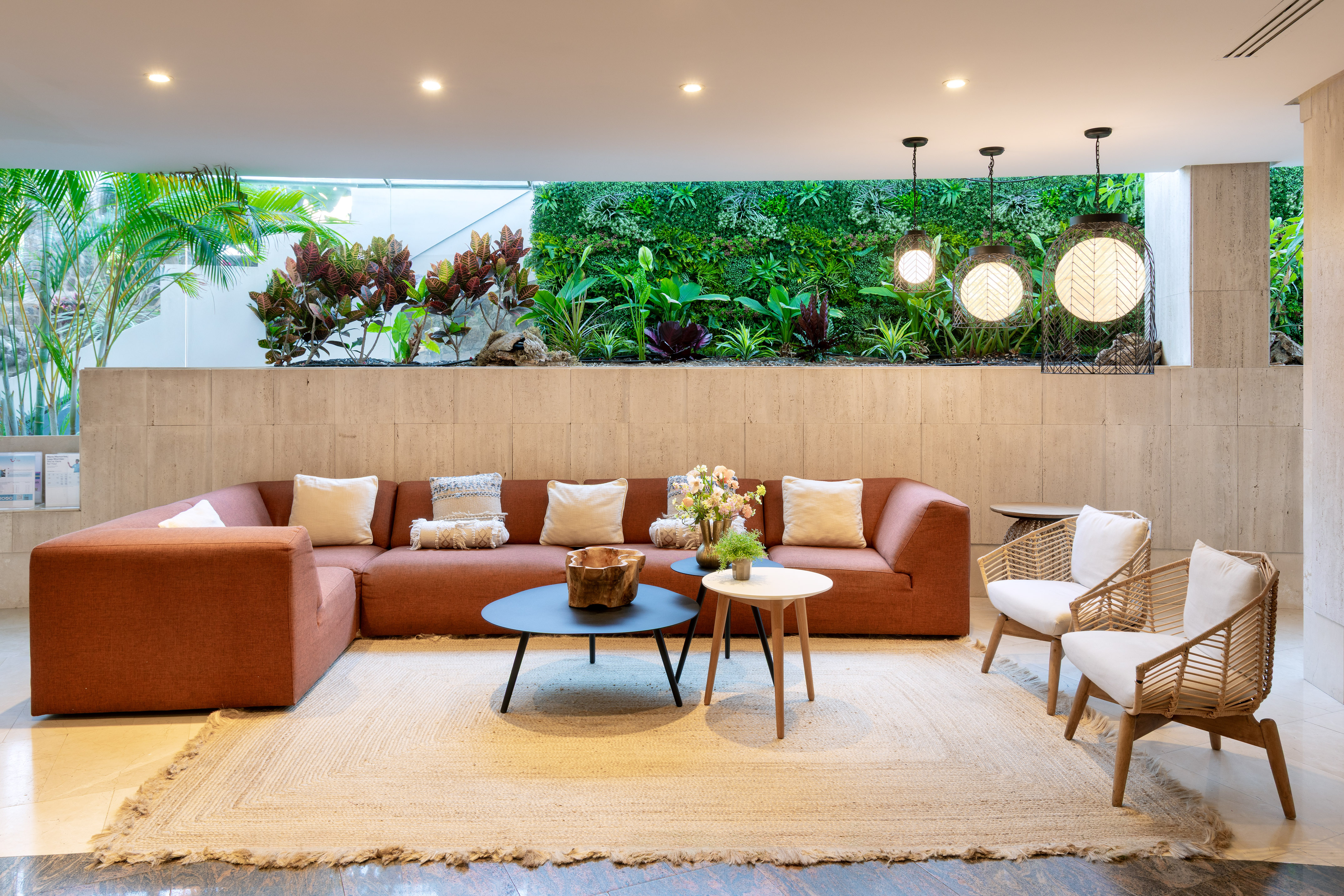 Hotel lounge with orange sectional sofa, rattan chairs, and green living wall.