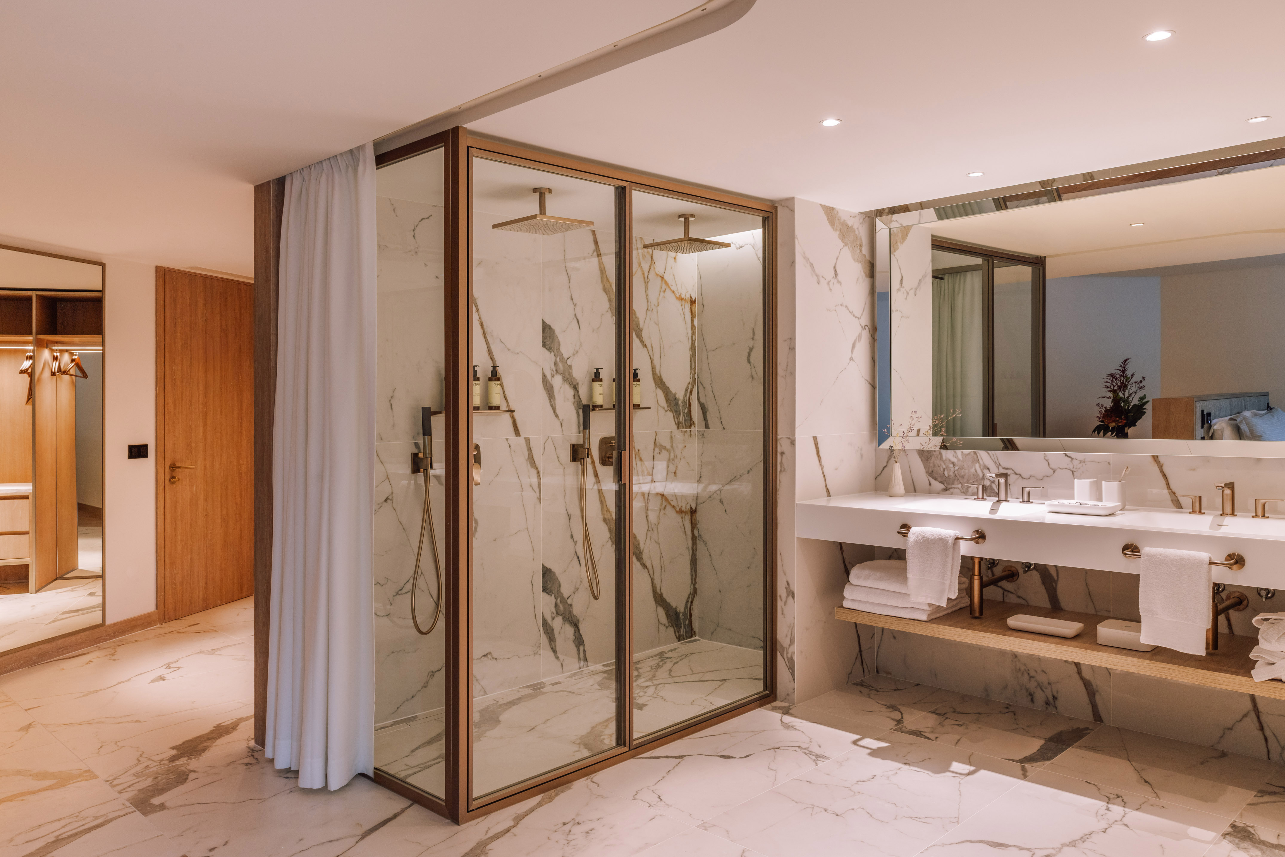 Luxury hotel bathroom with marble, double glass shower, and vanity area.