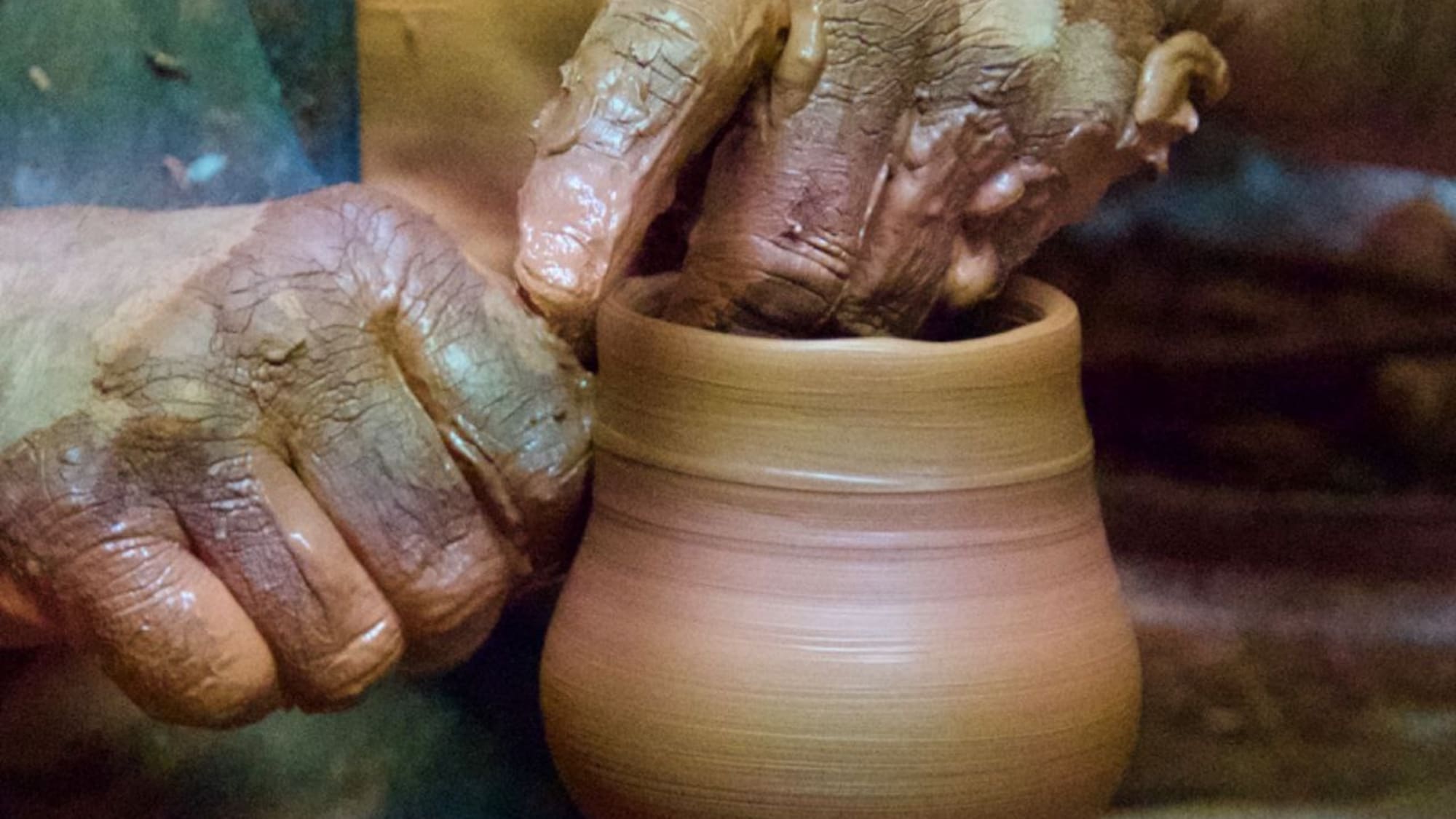 a person's hands touching a clay pot