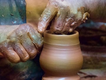 a person's hands touching a clay pot