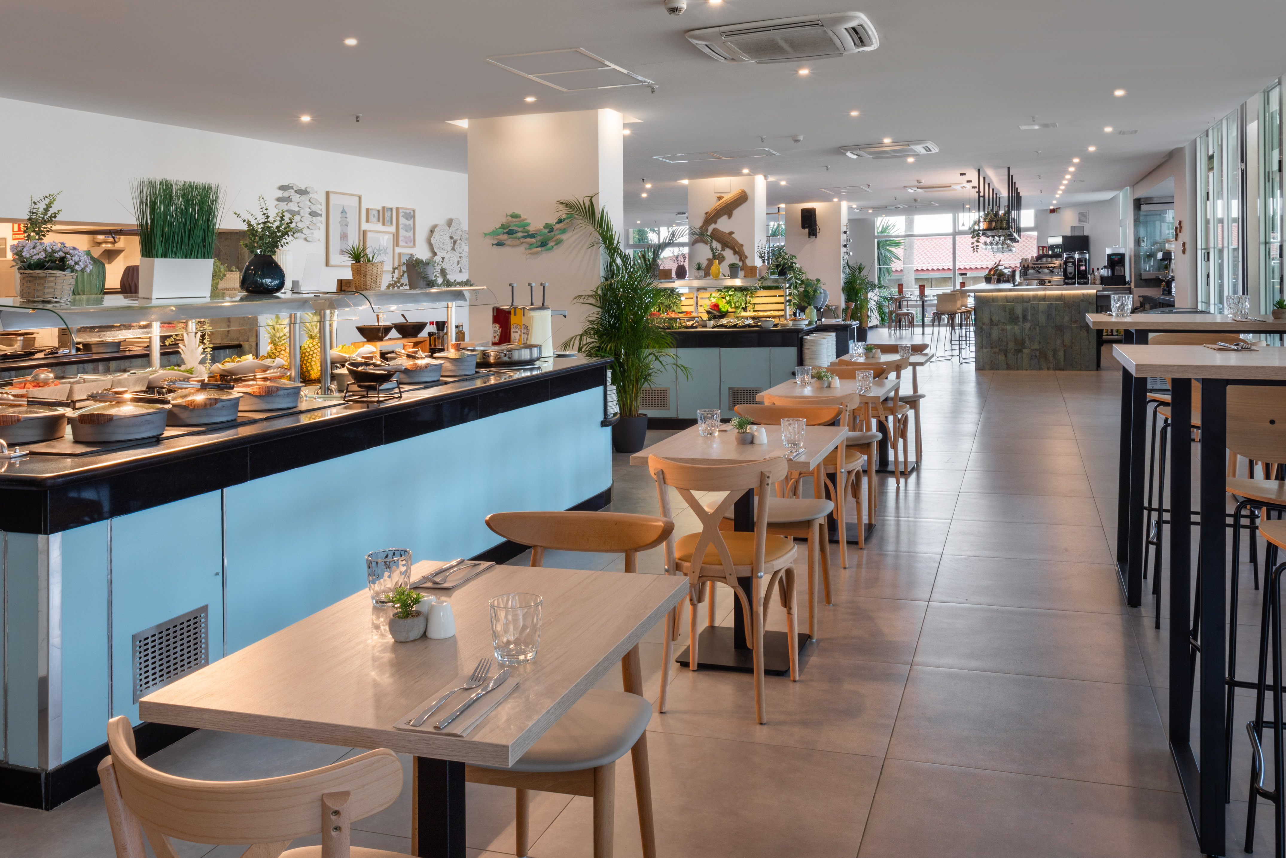 Modern hotel restaurant with extensive buffet, dining tables, and bar.