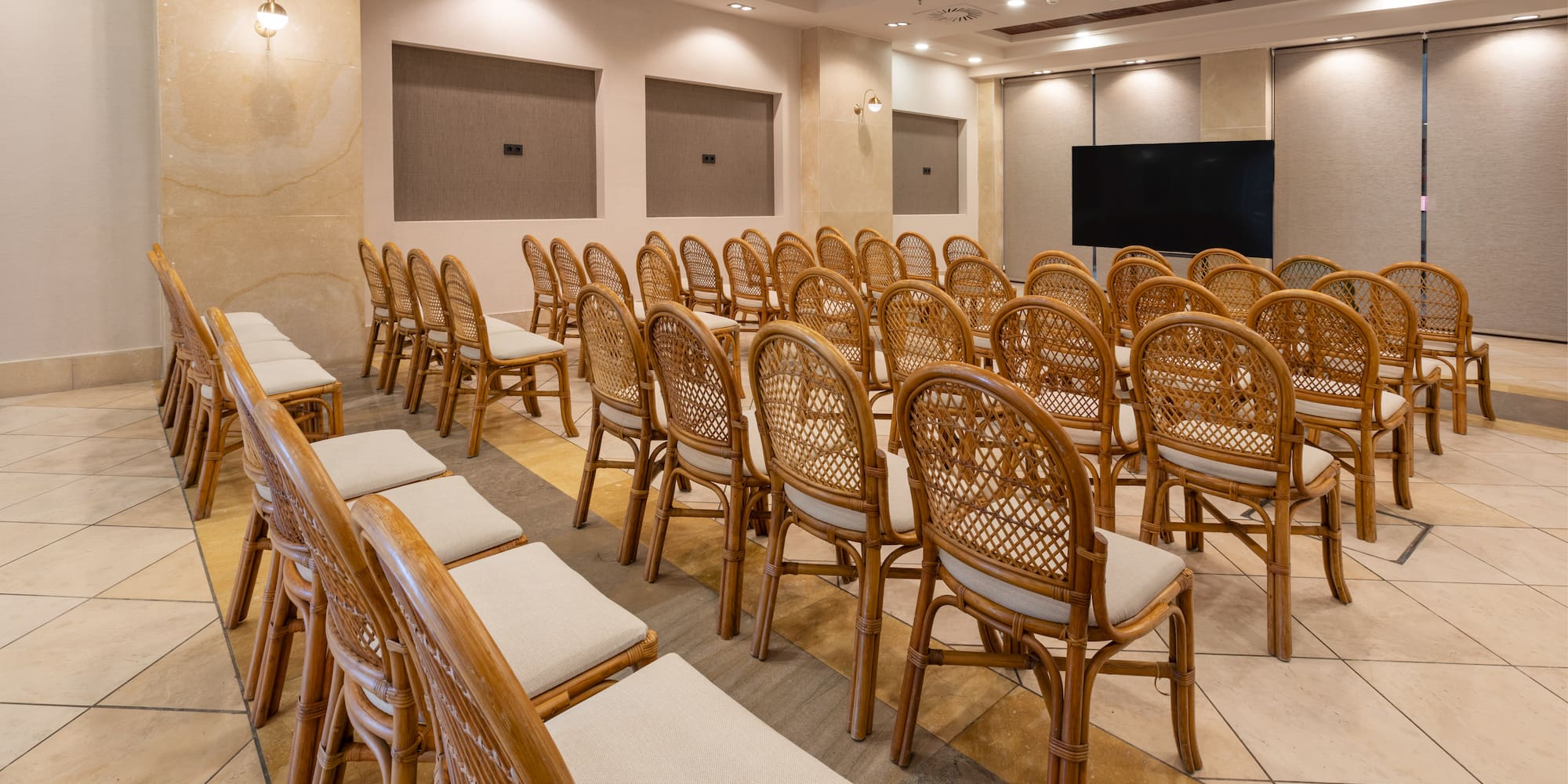 Empty modern conference room with rows of wicker chairs and a large screen.
