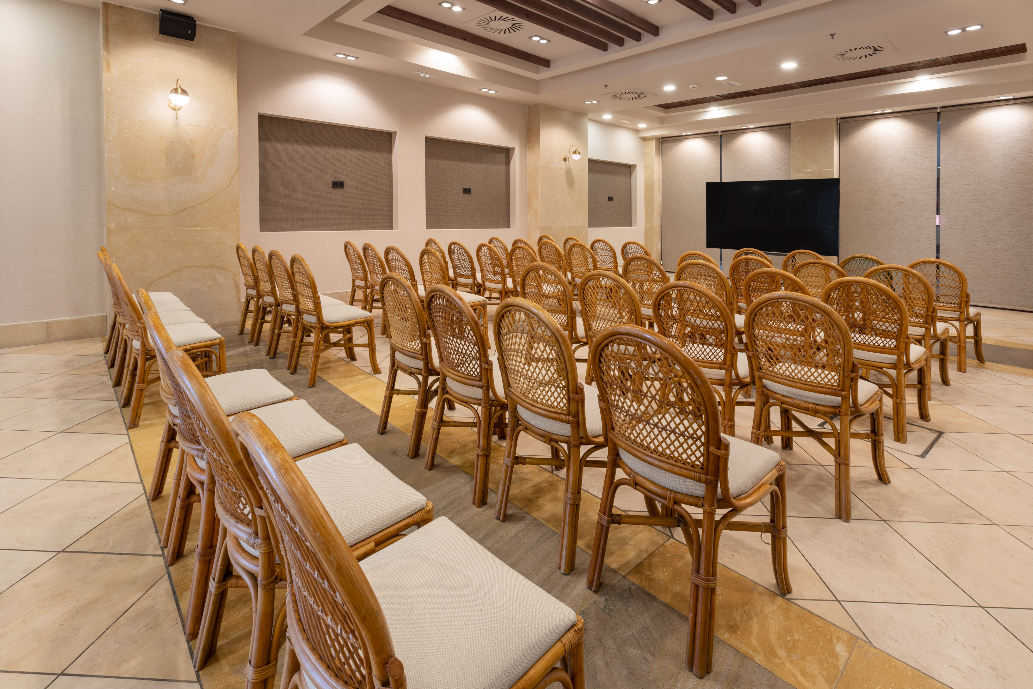 Empty modern conference room with rows of wicker chairs and a large screen.