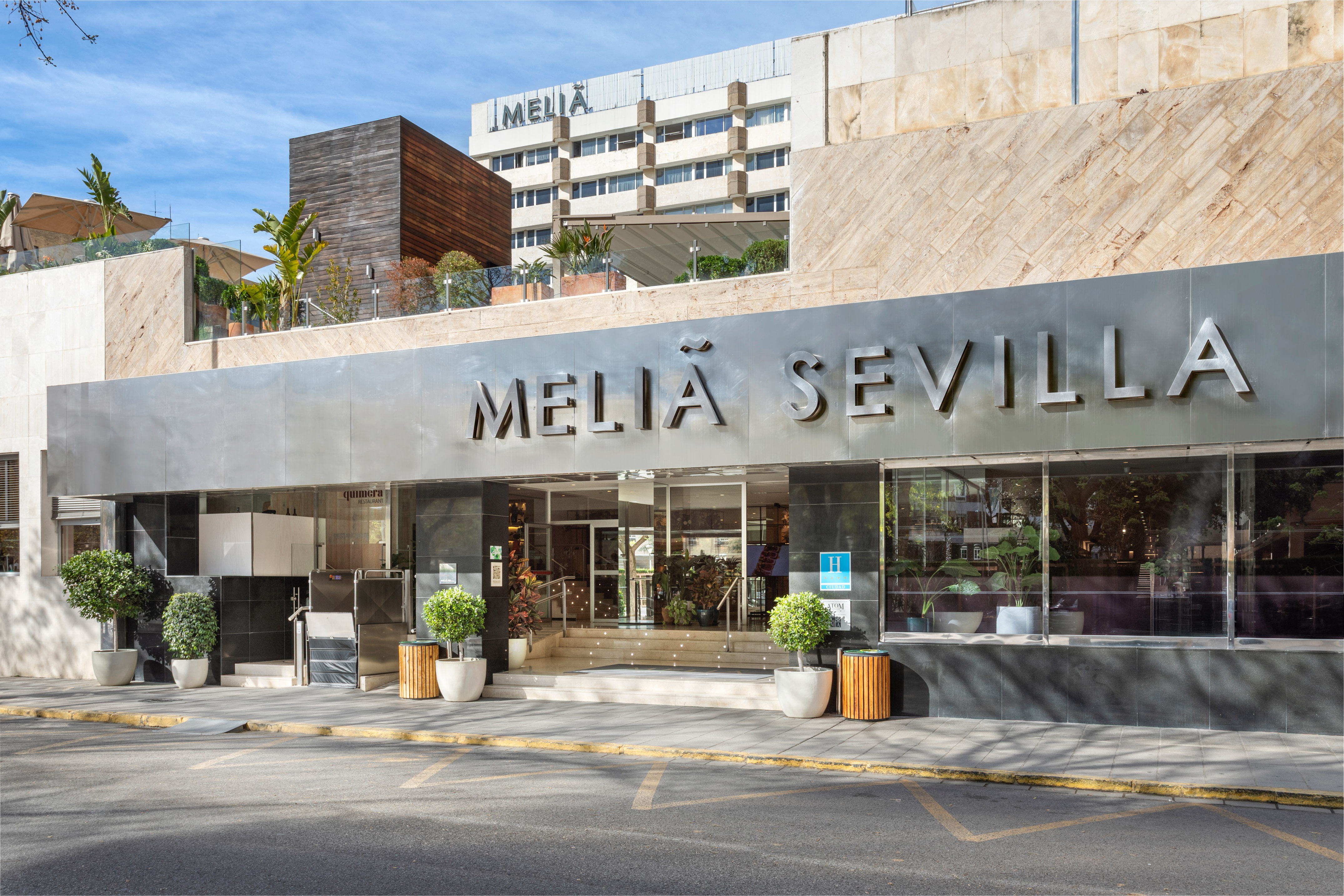 Meliá Sevilla hotel, modern glass entrance and facade from street level.