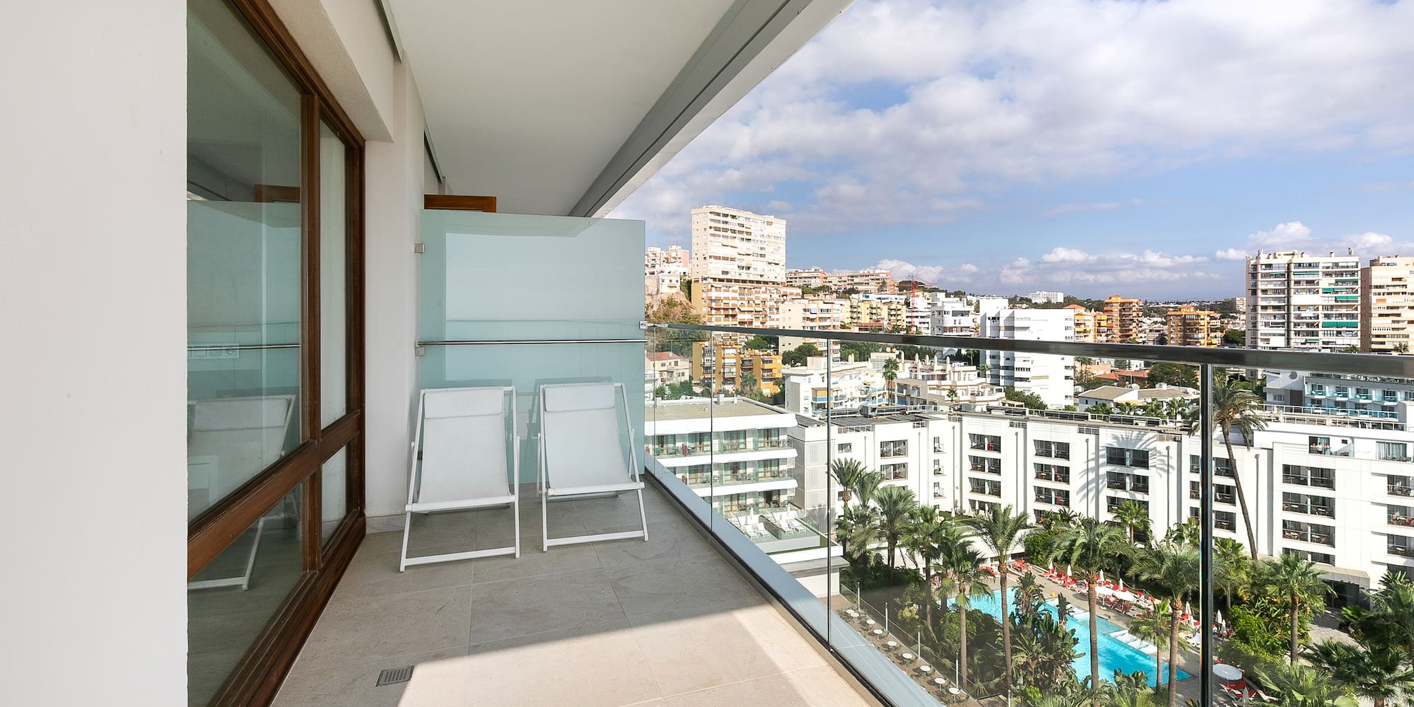 a balcony with chairs and a view of a city