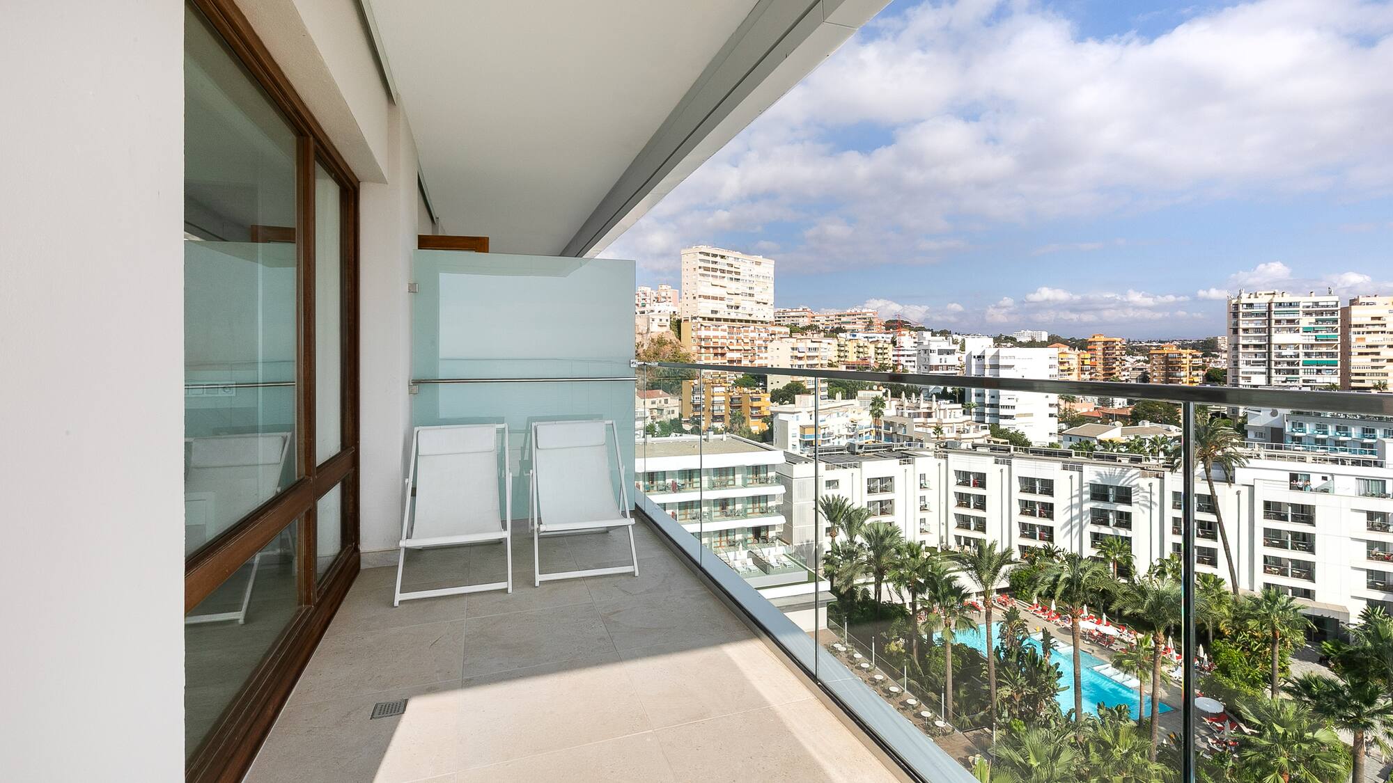 a balcony with chairs and a view of a city