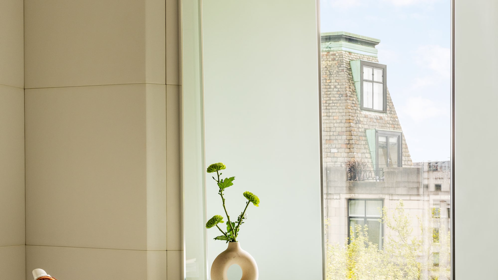 a glass table with a vase on it and a chair by a window