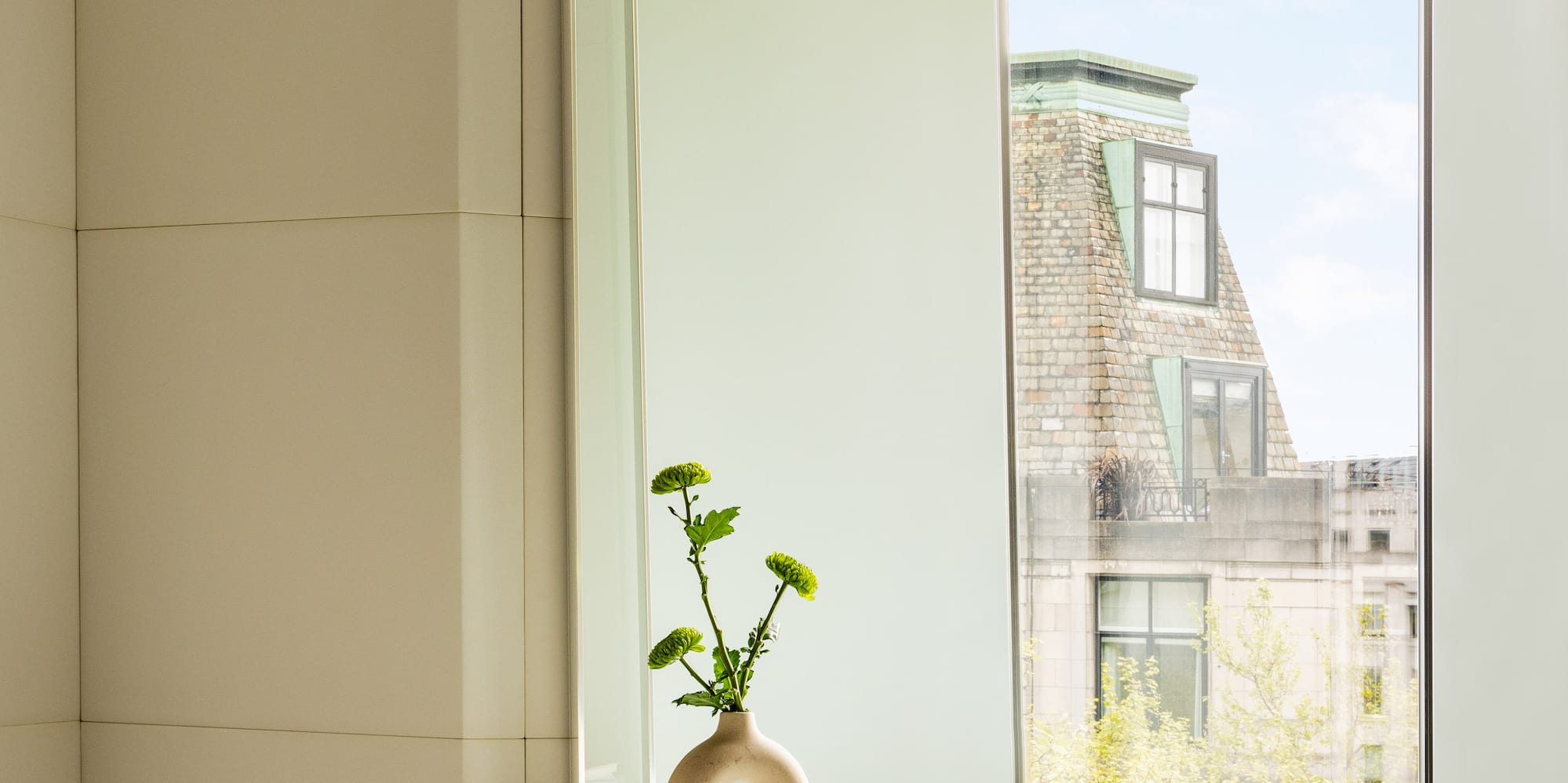 a glass table with a vase on it and a chair by a window