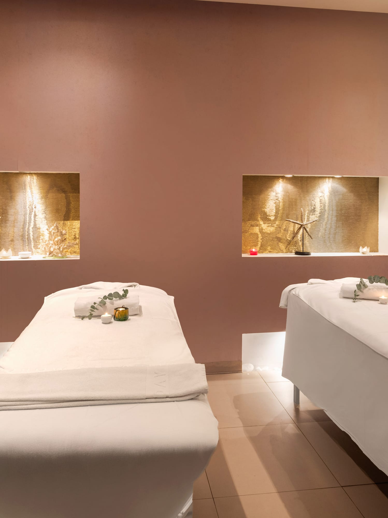 Luxurious spa massage room with two treatment beds and warm decorative lighting.