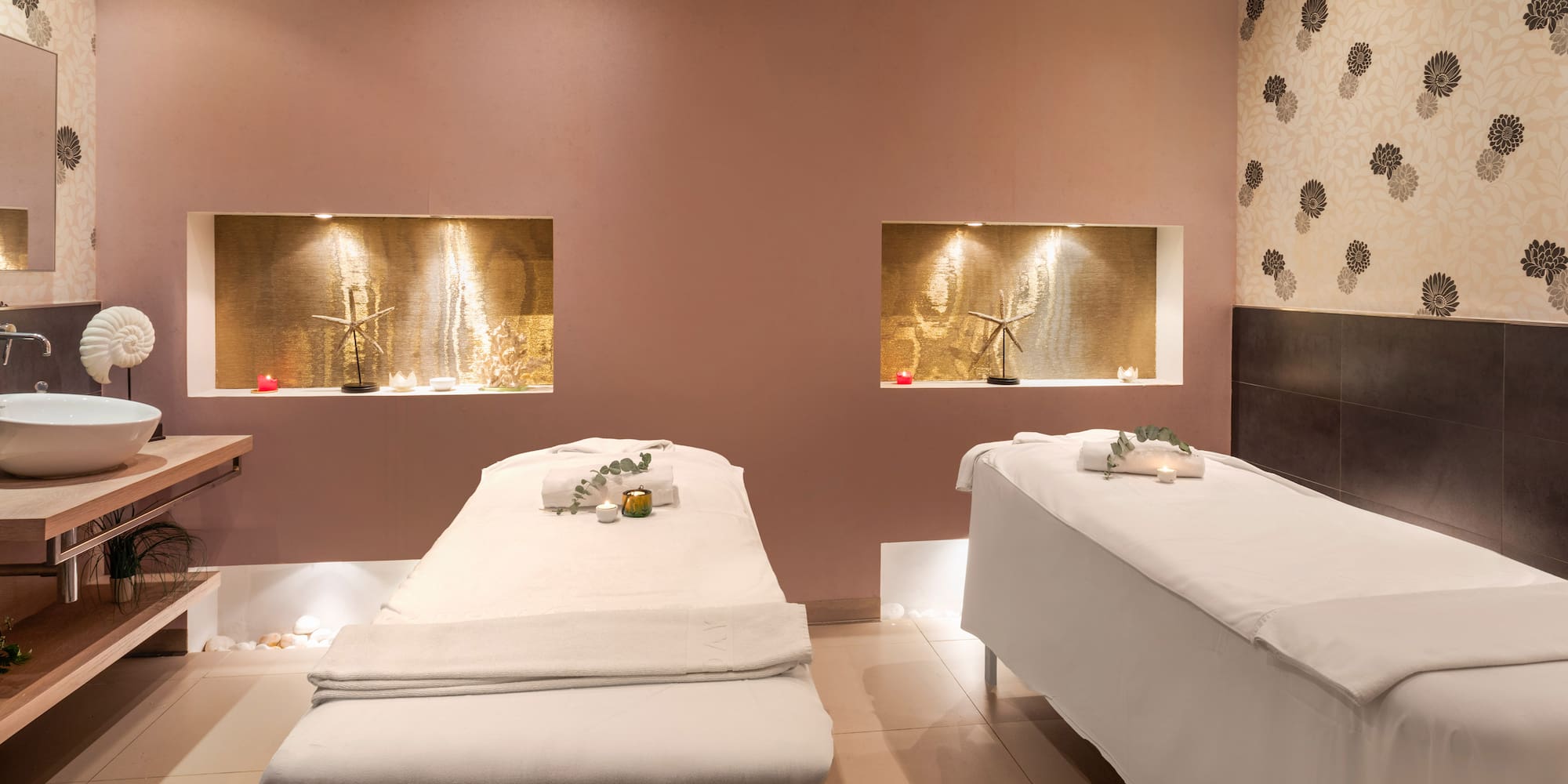 Spa treatment room with two massage beds, ambient lighting, and elegant decor.