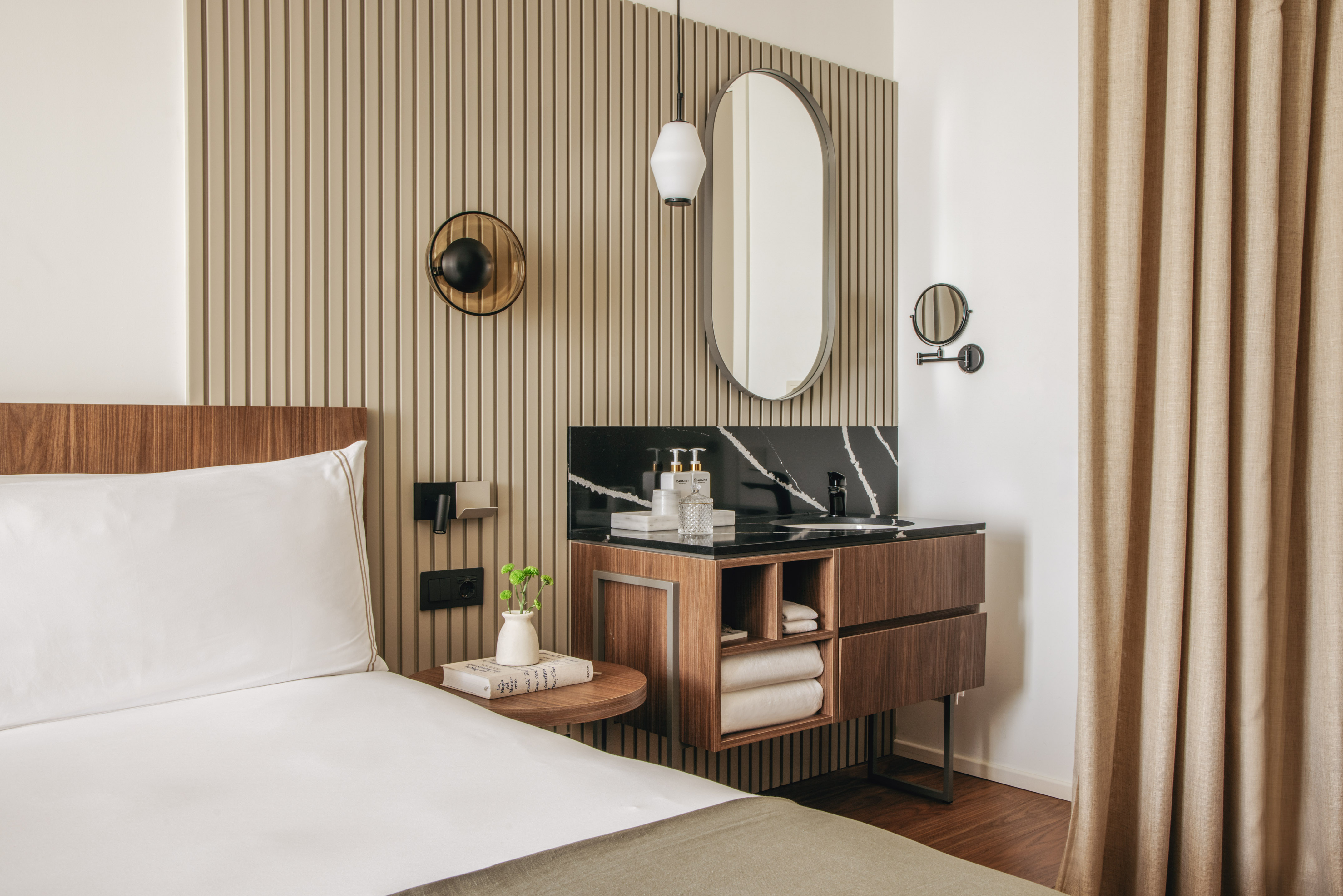 Modern hotel bedroom with wood slatted wall, white bed, and vanity unit.