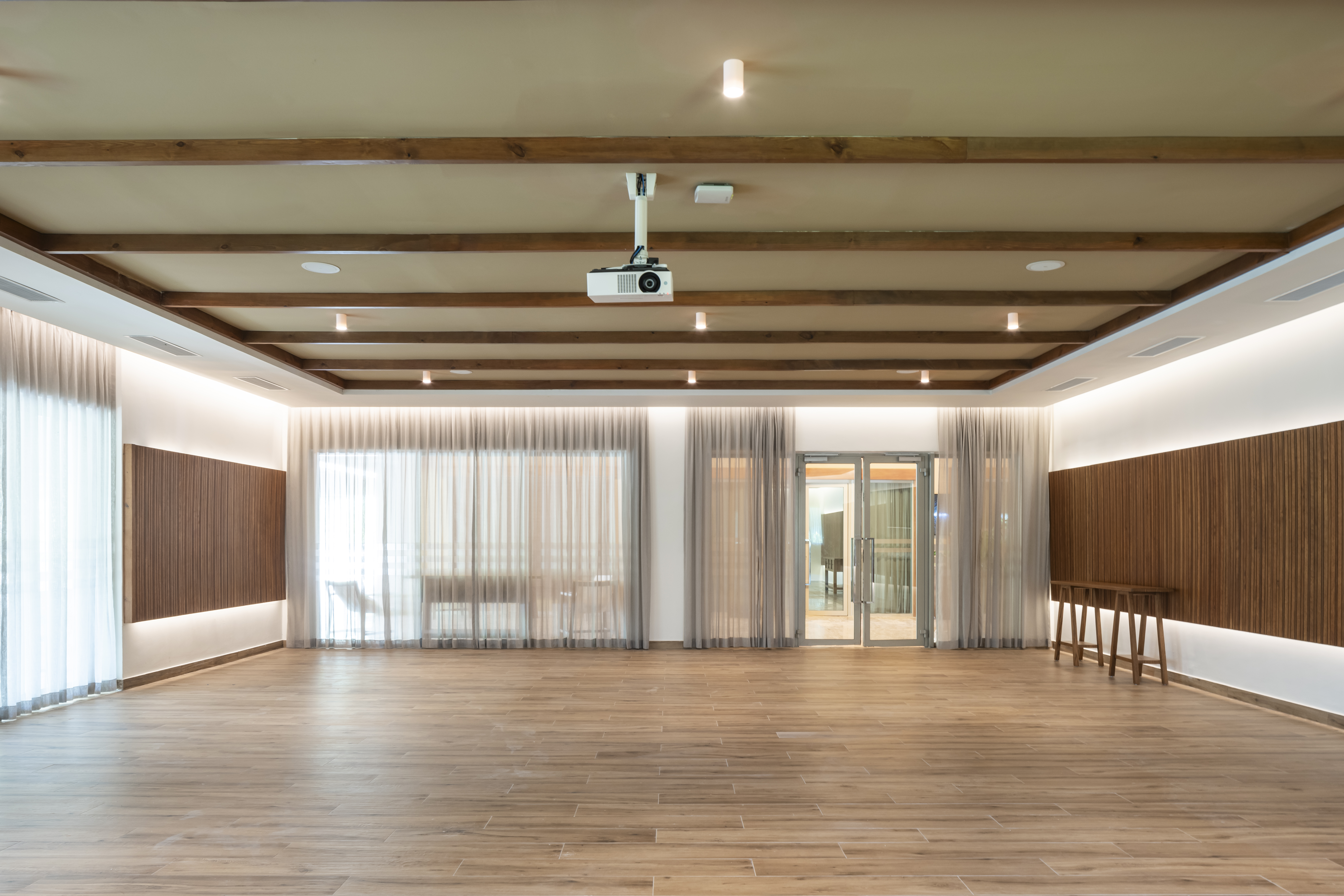 Empty modern event space with wood floor, ceiling beams, projector.