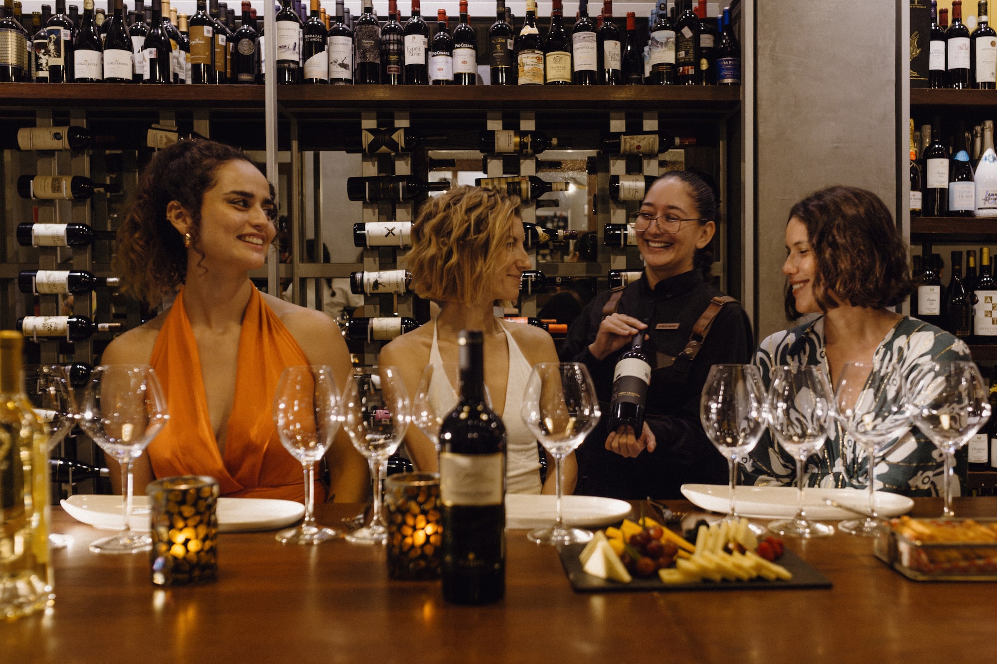 Women enjoying wine tasting with sommelier in a wine cellar.
