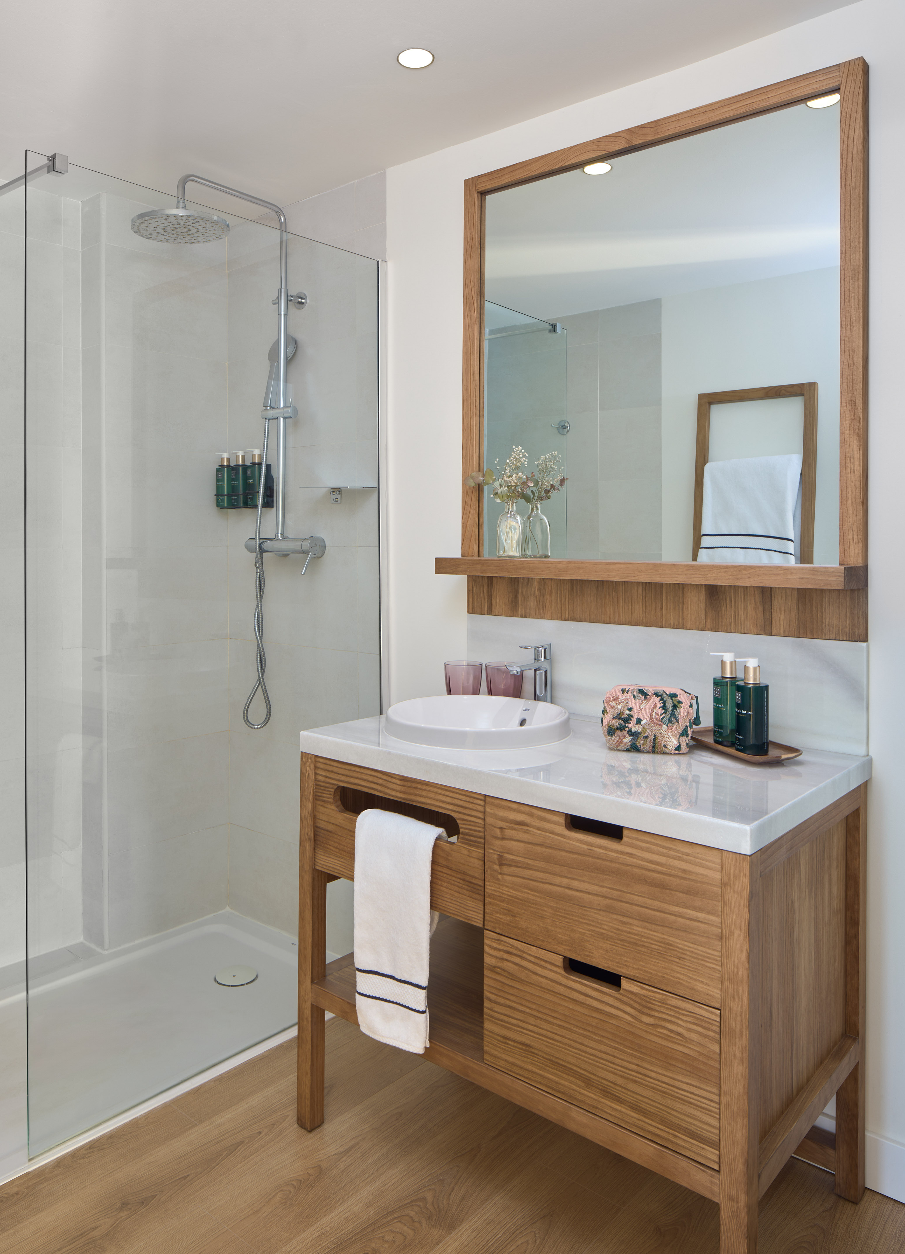 Modern bathroom with glass shower, wood vanity, white sink, and large mirror.