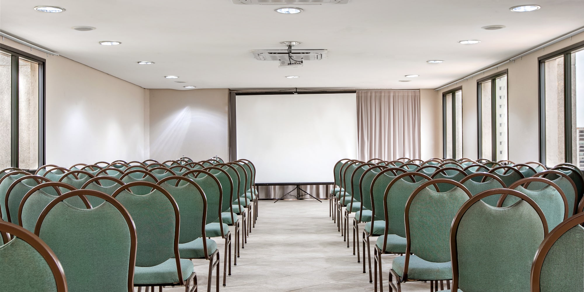 a room with green chairs and a projector screen