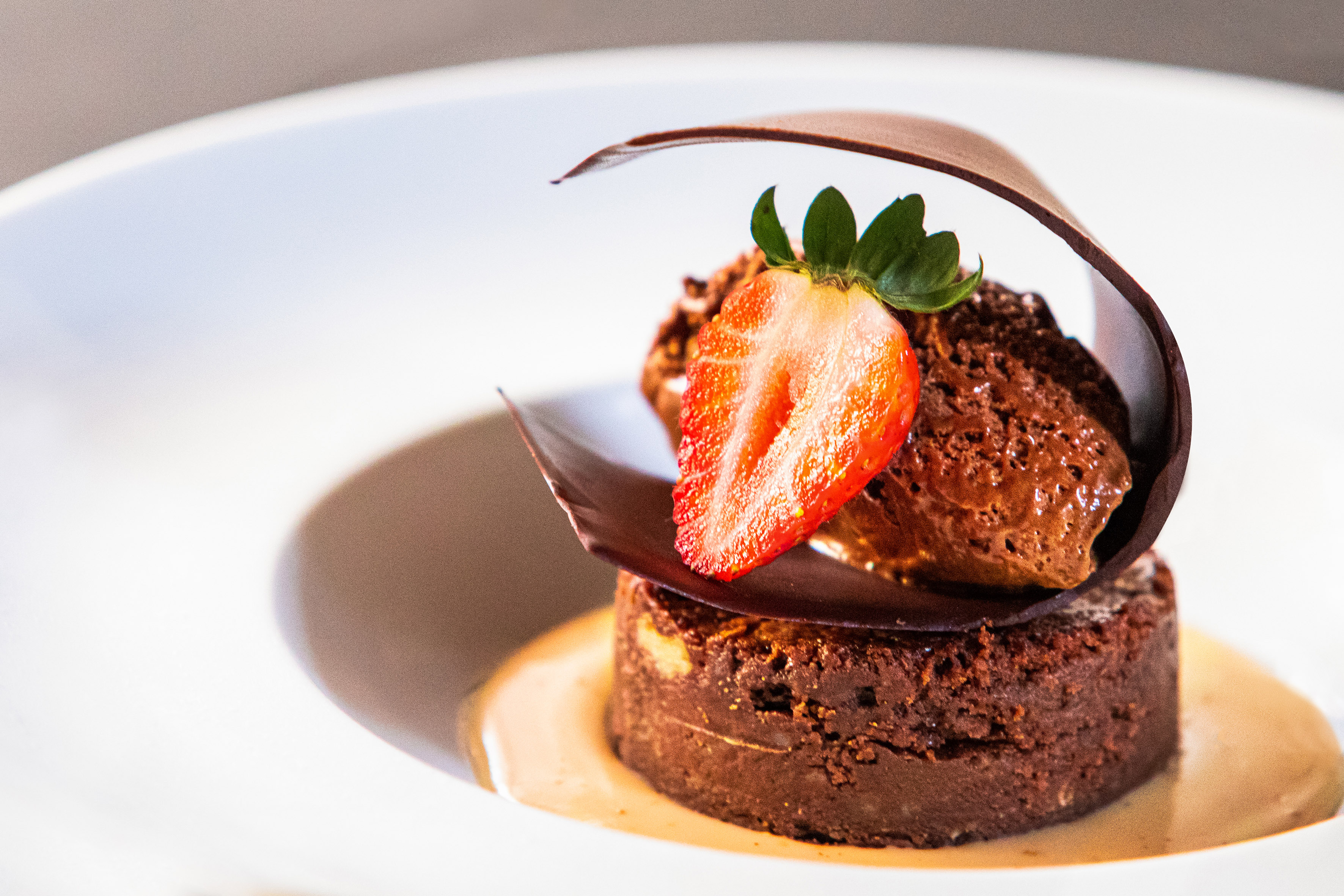 Decadent chocolate dessert with strawberry, mousse, and chocolate curl.