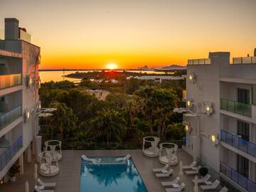Luxurious Ibiza hotel pool at sunset, overlooking the sea and islands.