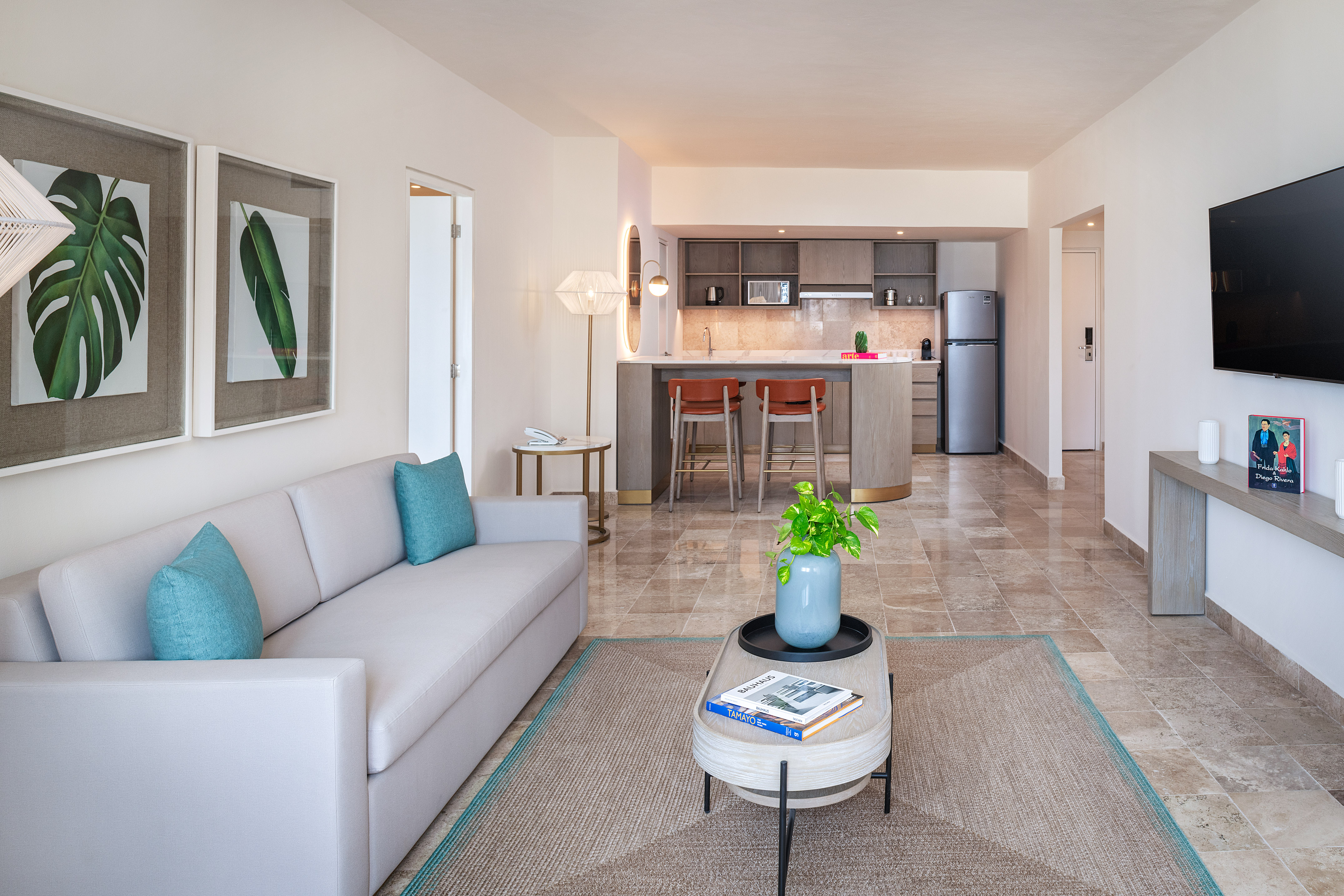 Bright open-concept living room and kitchen in a modern suite with sofa and bar.