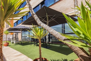 a building with palm trees and umbrellas