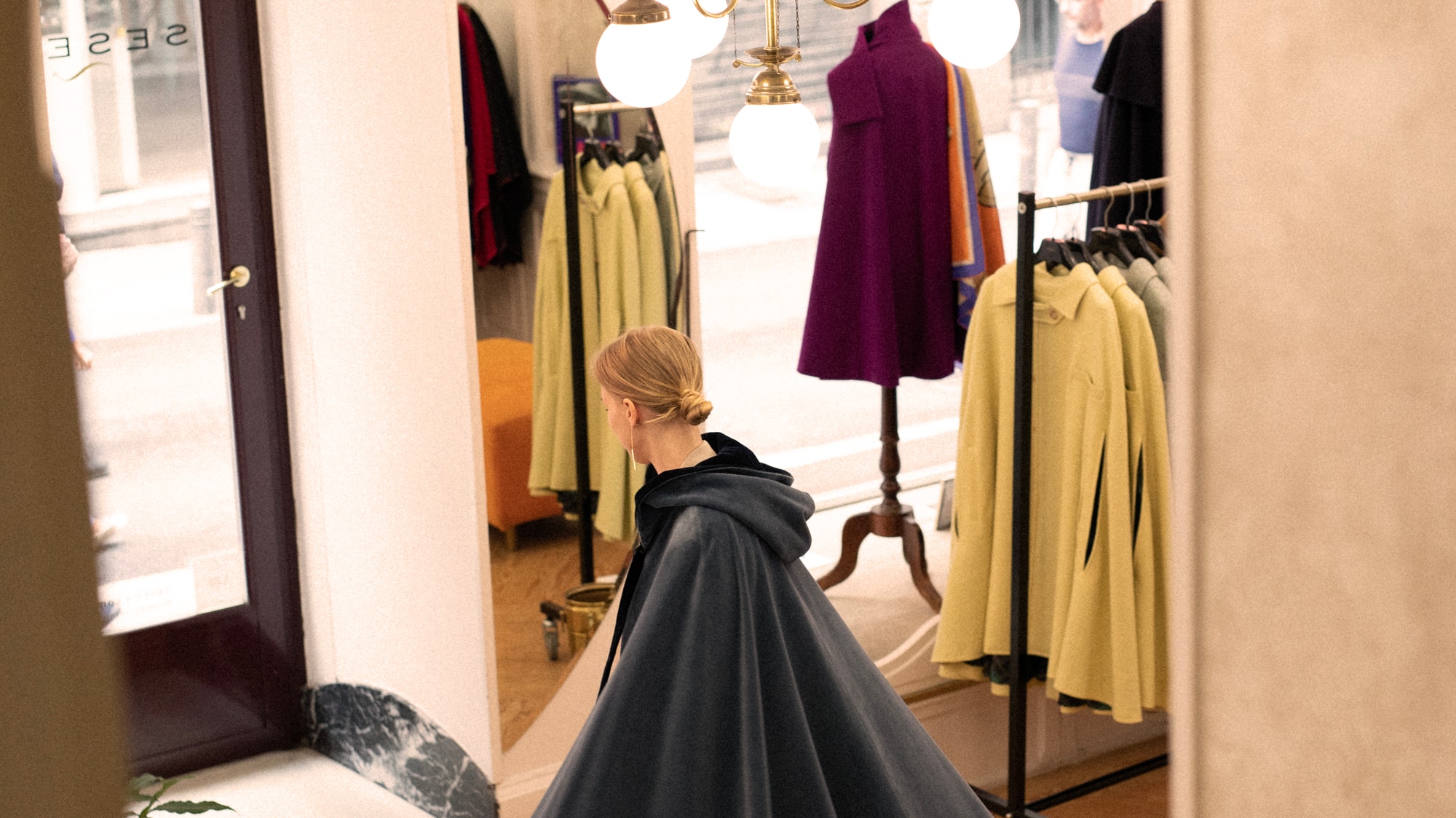 a woman in a cape walking in a store
