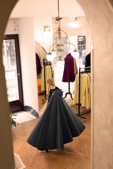 a woman in a cape walking in a store