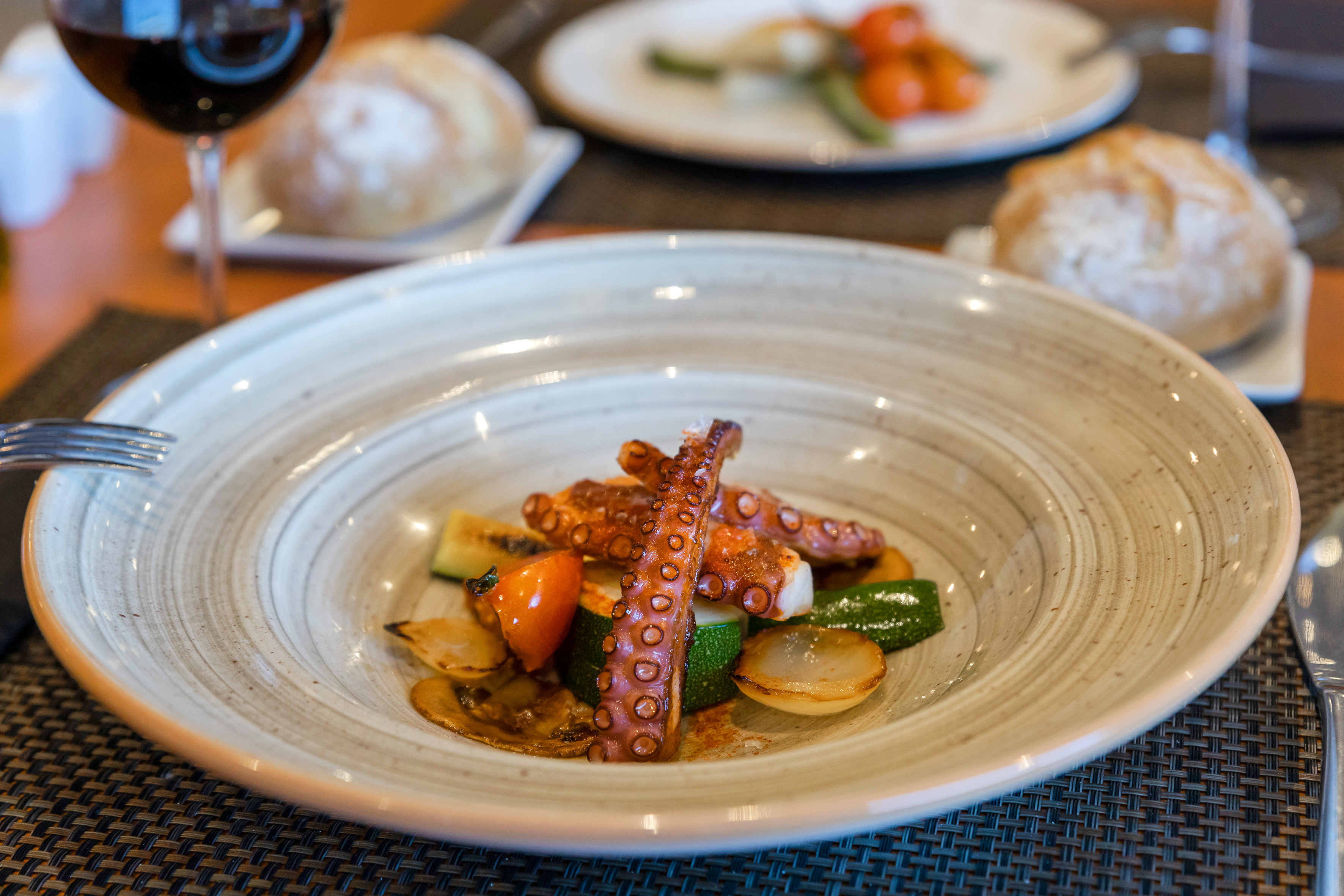 Grilled octopus with roasted zucchini, tomatoes, and onions.