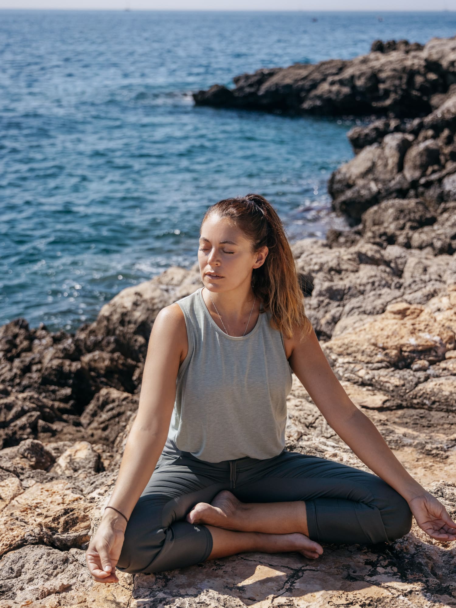 a woman sitting on rocks near water