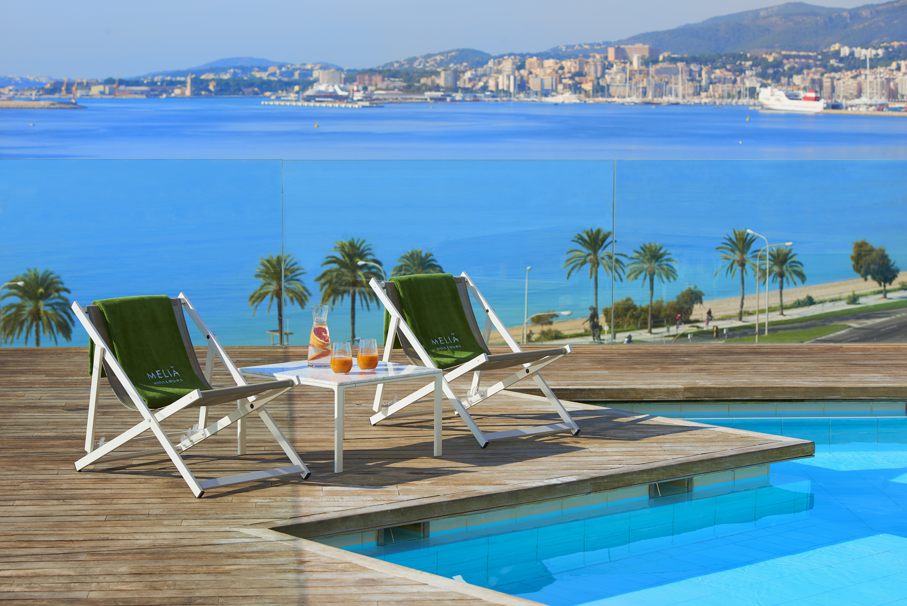 Meliá resort pool deck, lounge chairs, drinks, scenic bay cityscape.