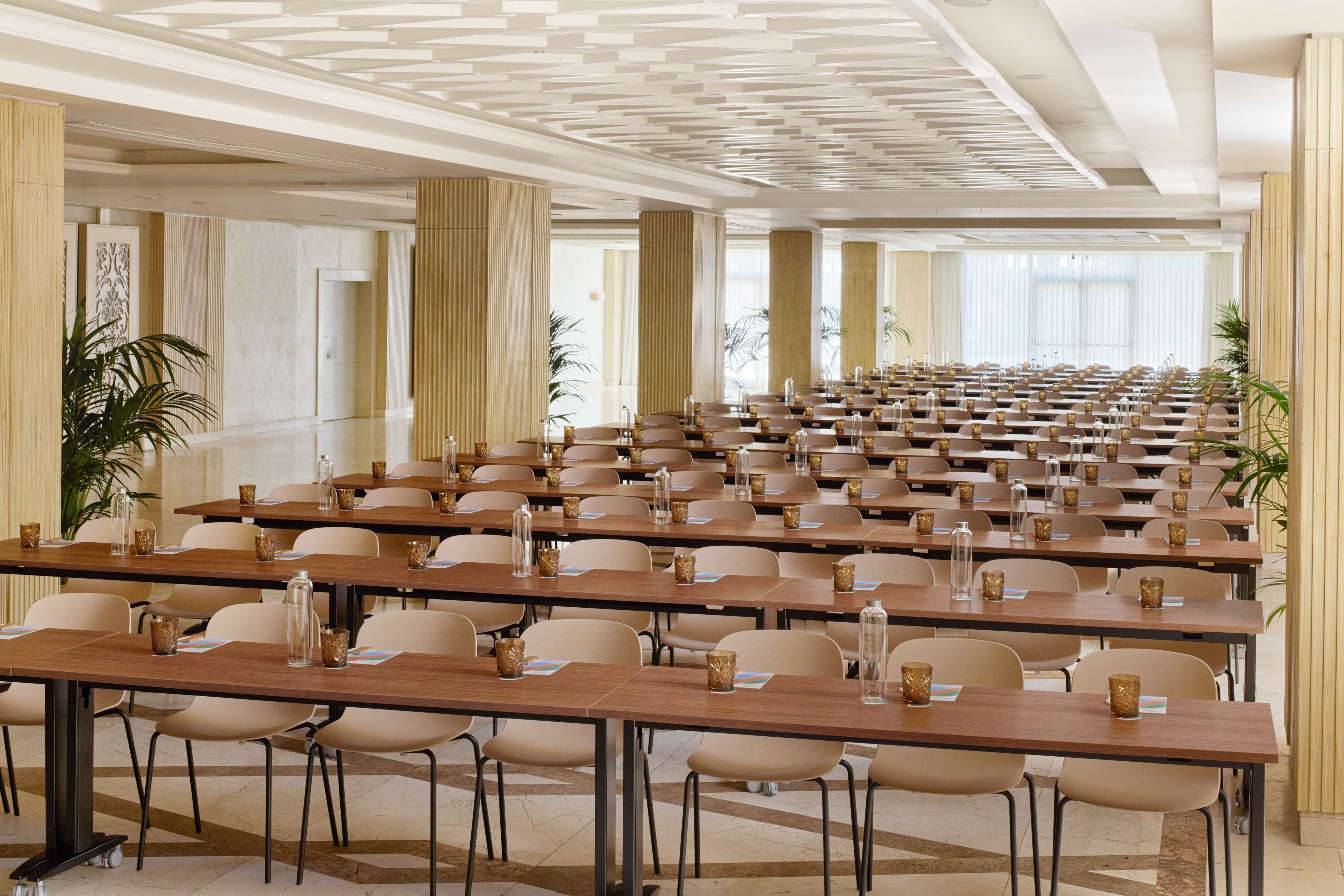 Large conference room with neat rows of tables, chairs, and water bottles.