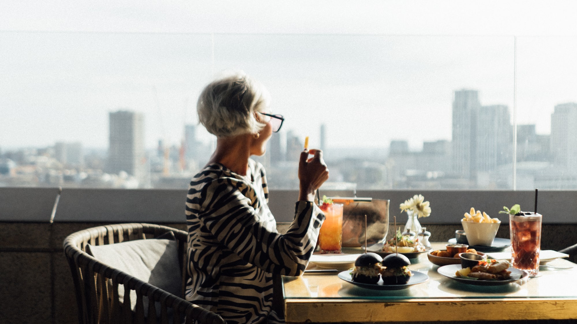A woman is seated at a table covered with food.