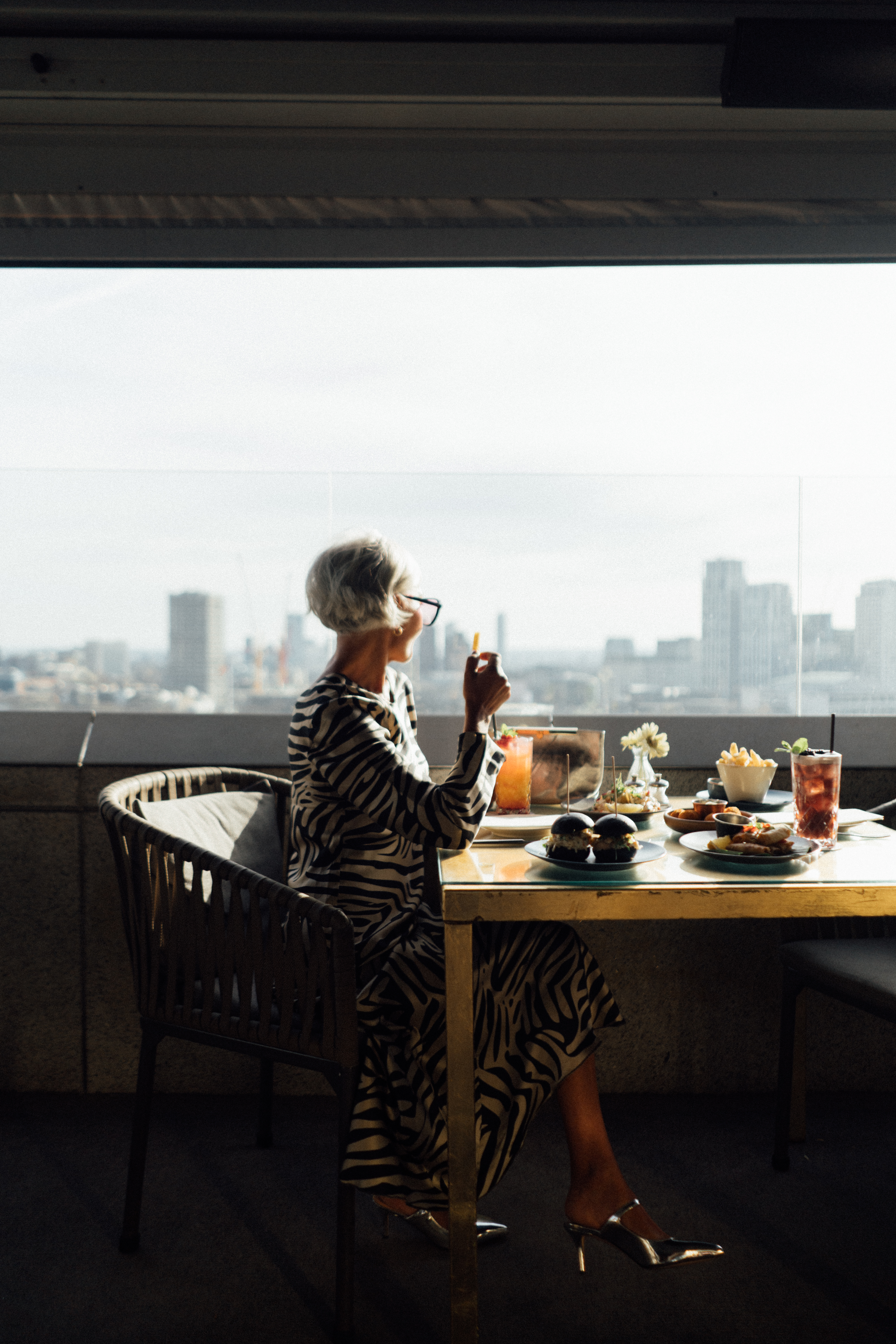A woman is seated at a table covered with food.