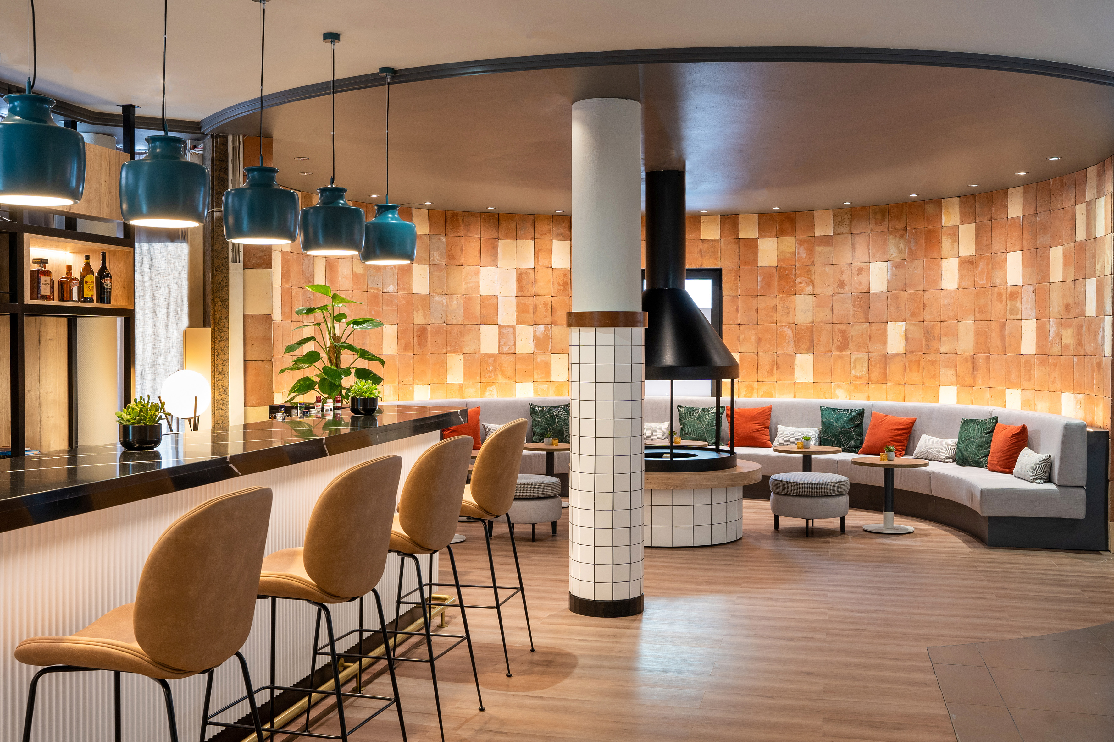 Modern lounge bar area with terracotta brick wall, fireplace, and bar counter.