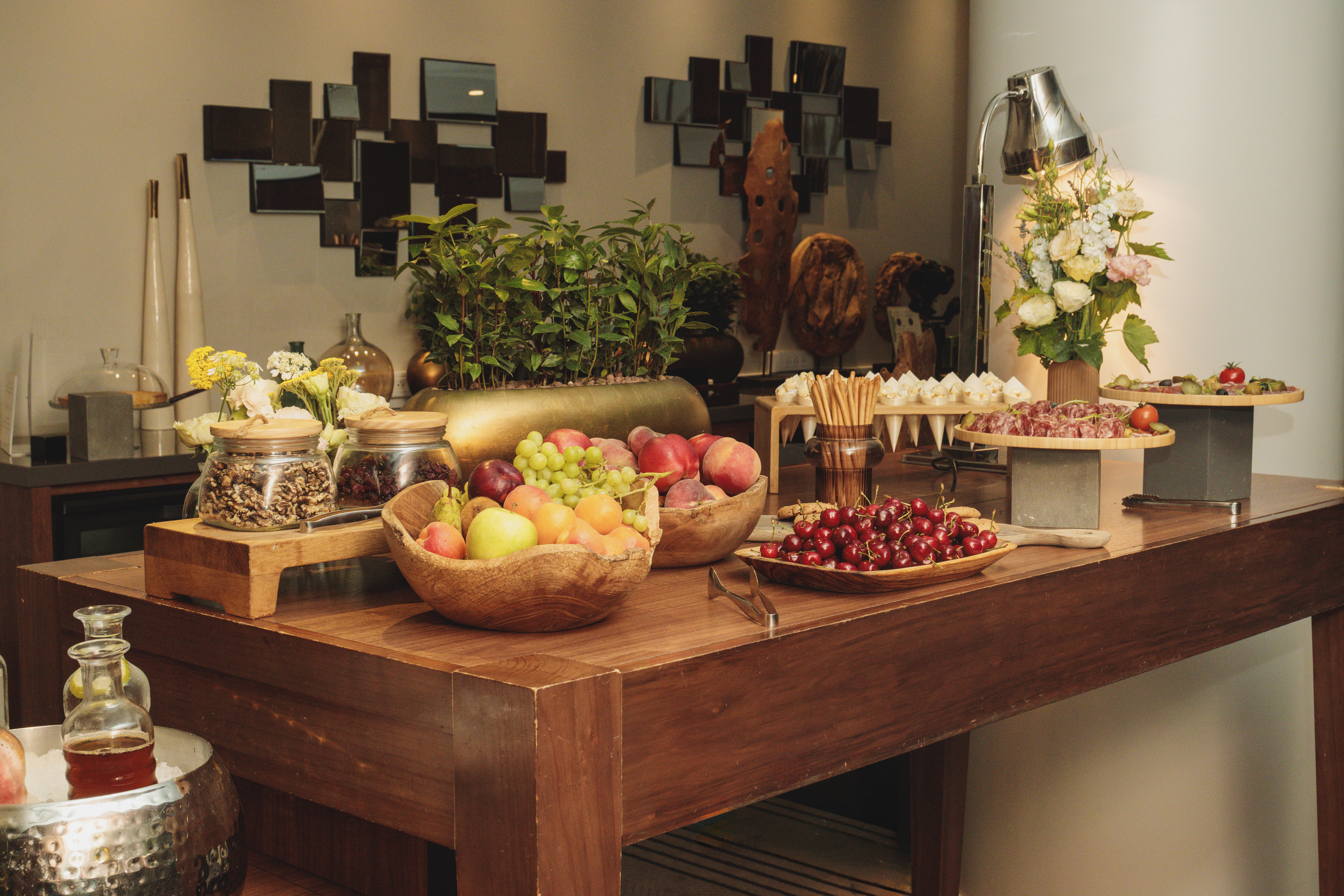 Luxurious buffet table with fresh fruit, charcuterie, nuts, and floral decor.