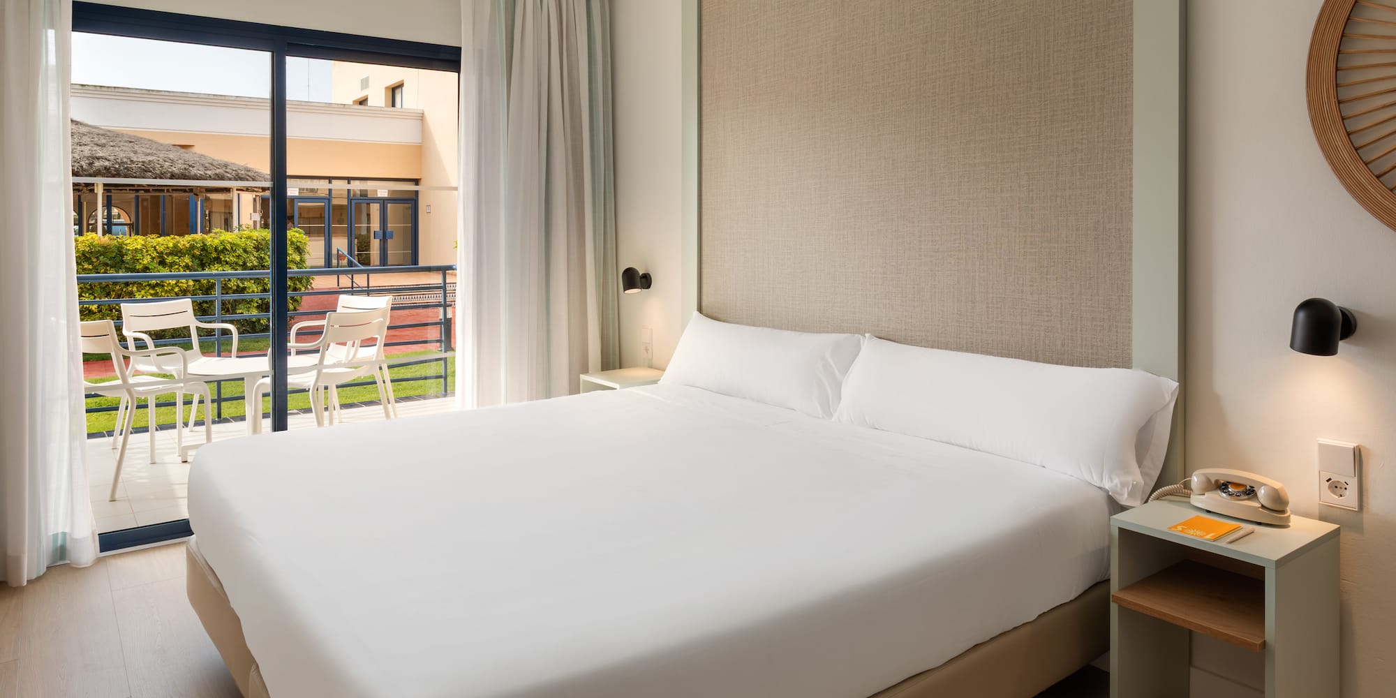 Hotel room with comfortable bed, balcony, and view of resort grounds.