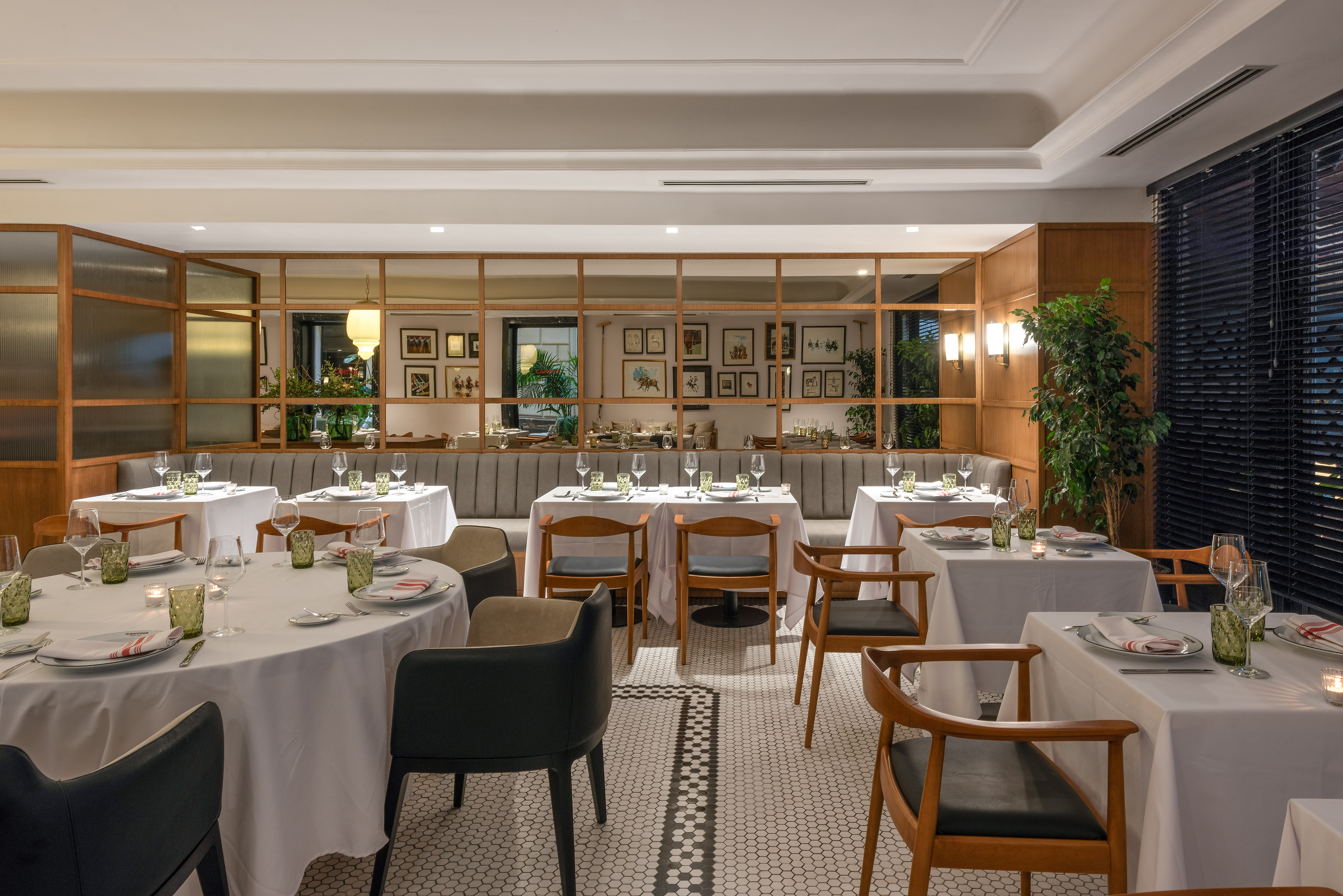 Elegant restaurant dining room with set tables, banquettes, and patterned tiled floor.