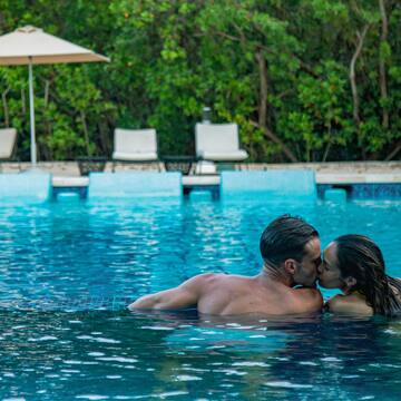 a man and woman kissing in a pool