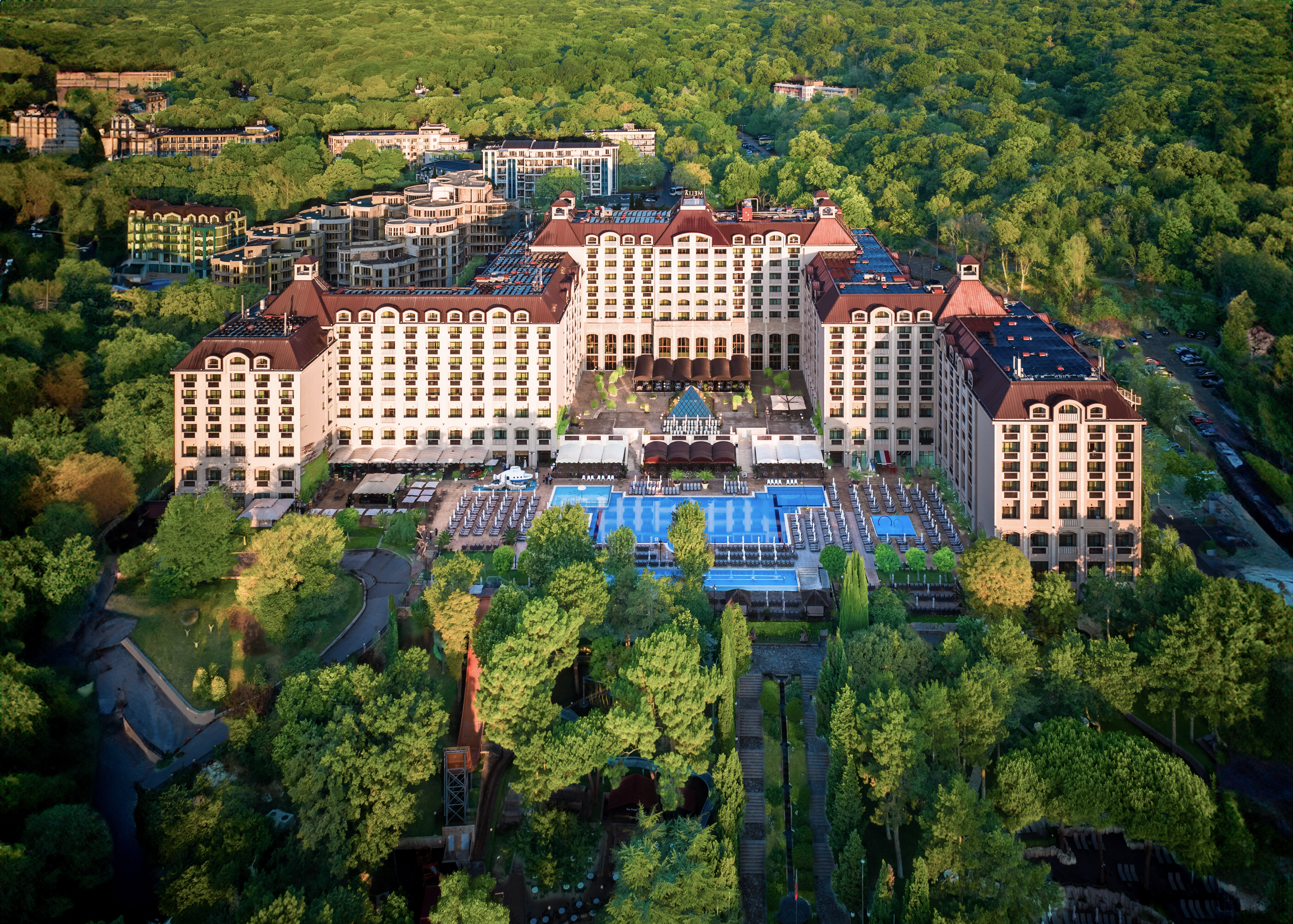a large building with a pool surrounded by trees
