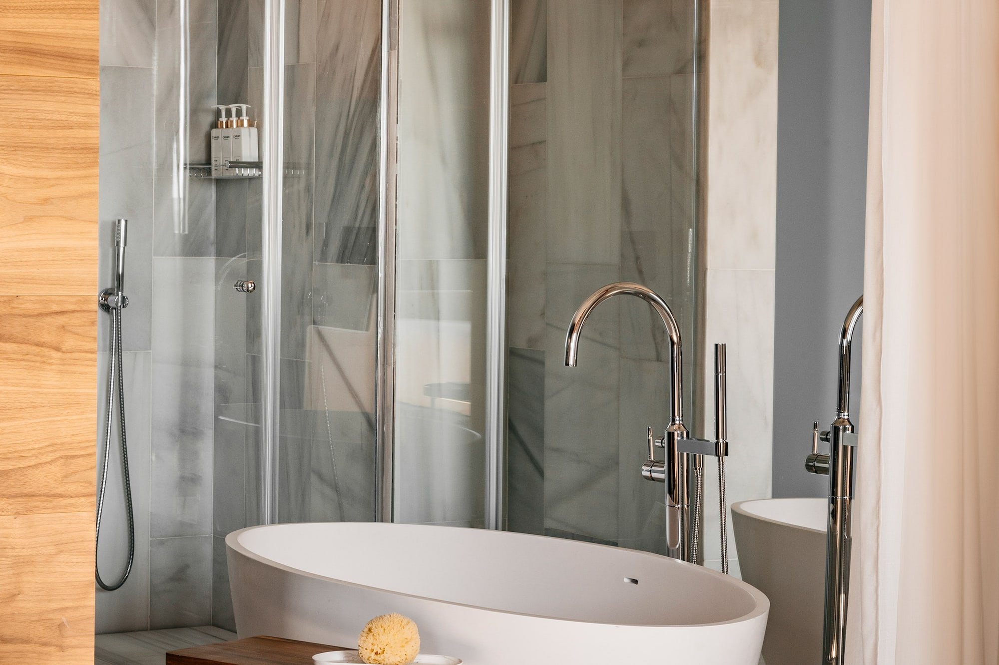 Modern luxury bathroom with freestanding tub, glass shower, marble walls, and wood accents. - Junior Suite RedLevel Uitzicht op de Kathedraal - Hotel Colón Gran Meliá, Sevilla