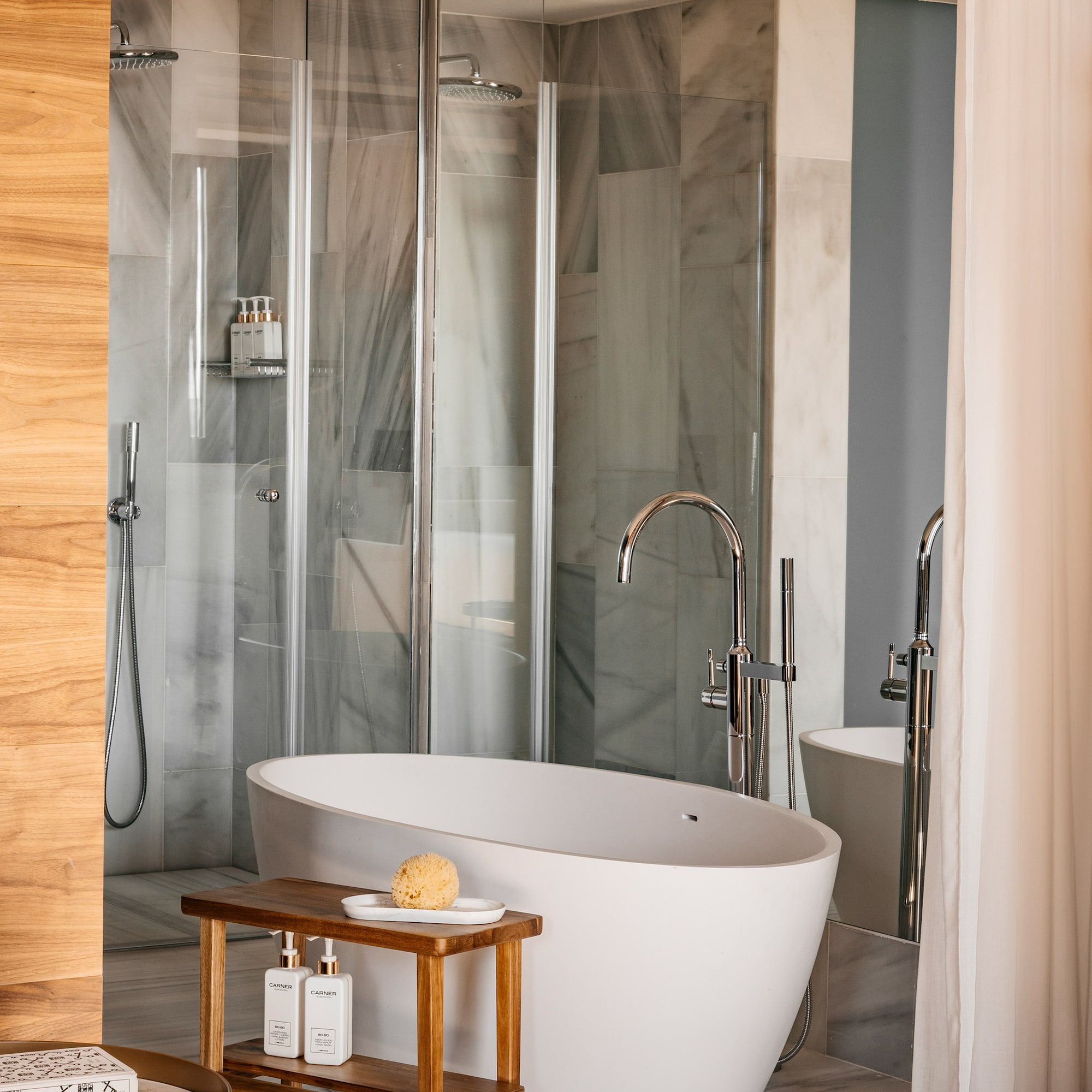 Modern luxury bathroom with freestanding tub, glass shower, marble walls, and wood accents. - Junior Suite RedLevel Uitzicht op de Kathedraal - Hotel Colón Gran Meliá, Sevilla