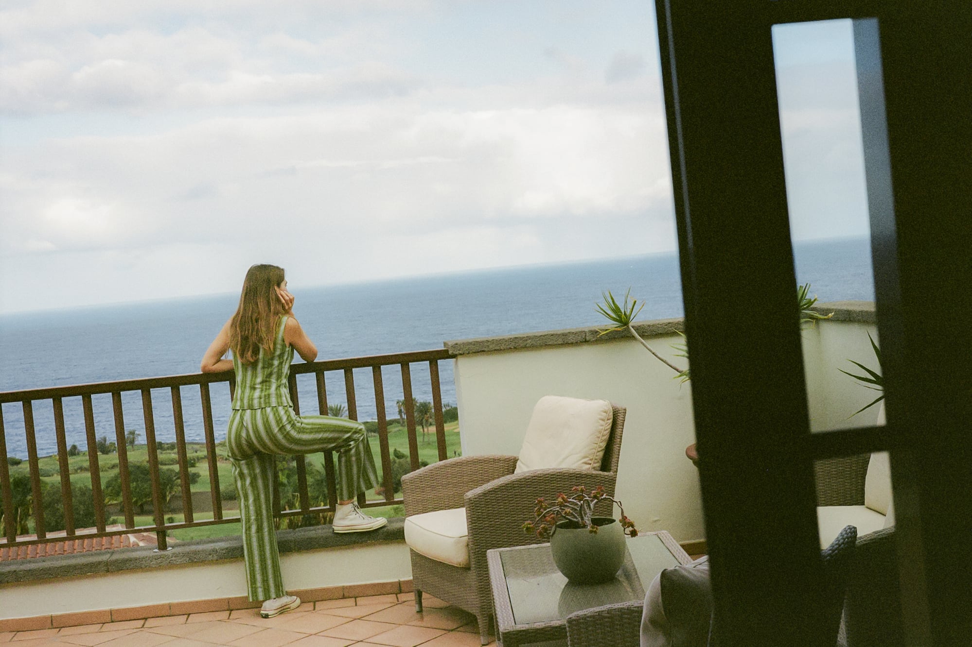 a woman standing on a balcony overlooking the ocean