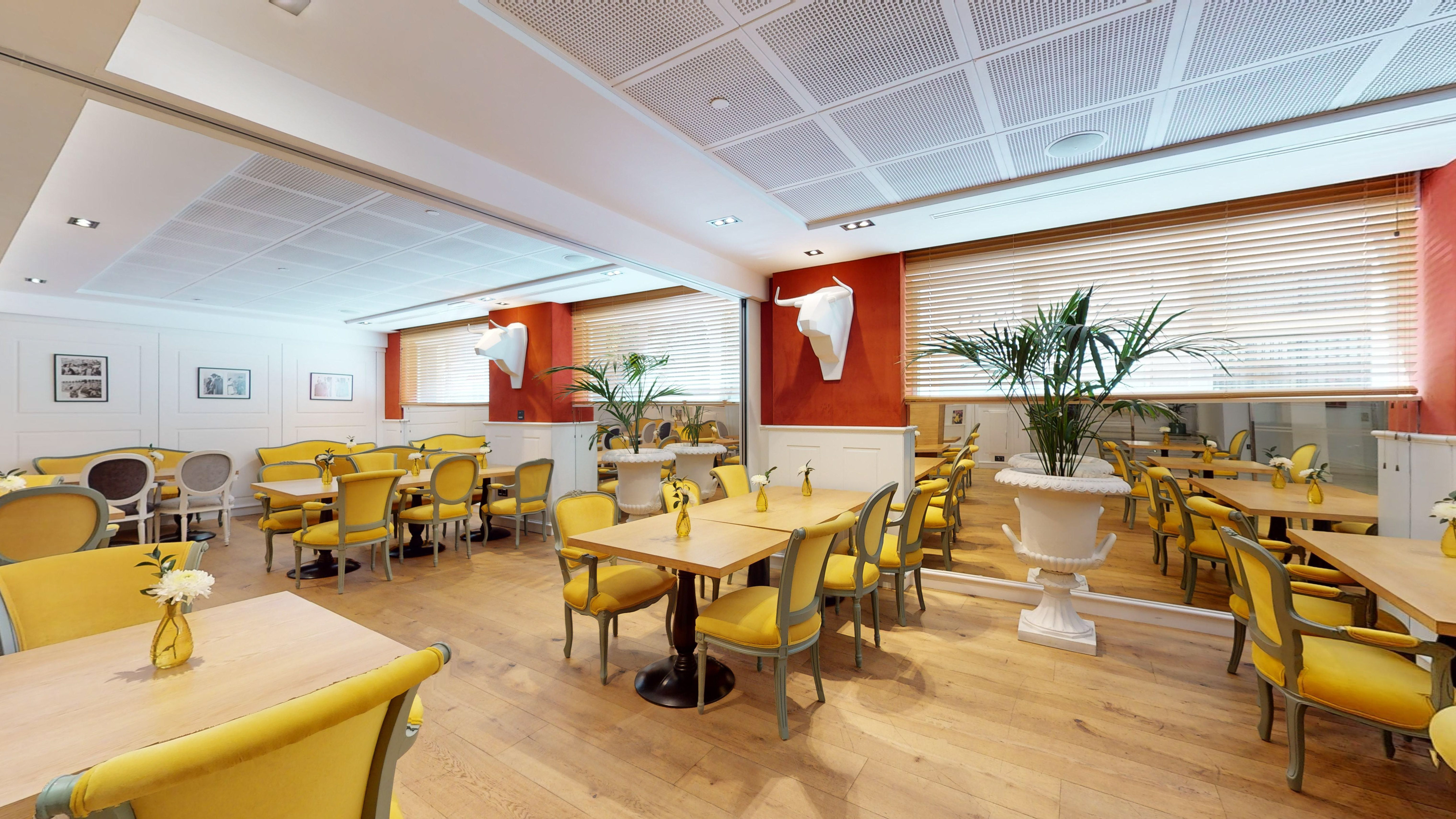 Restaurant dining room with yellow chairs, red walls, bull head decor.