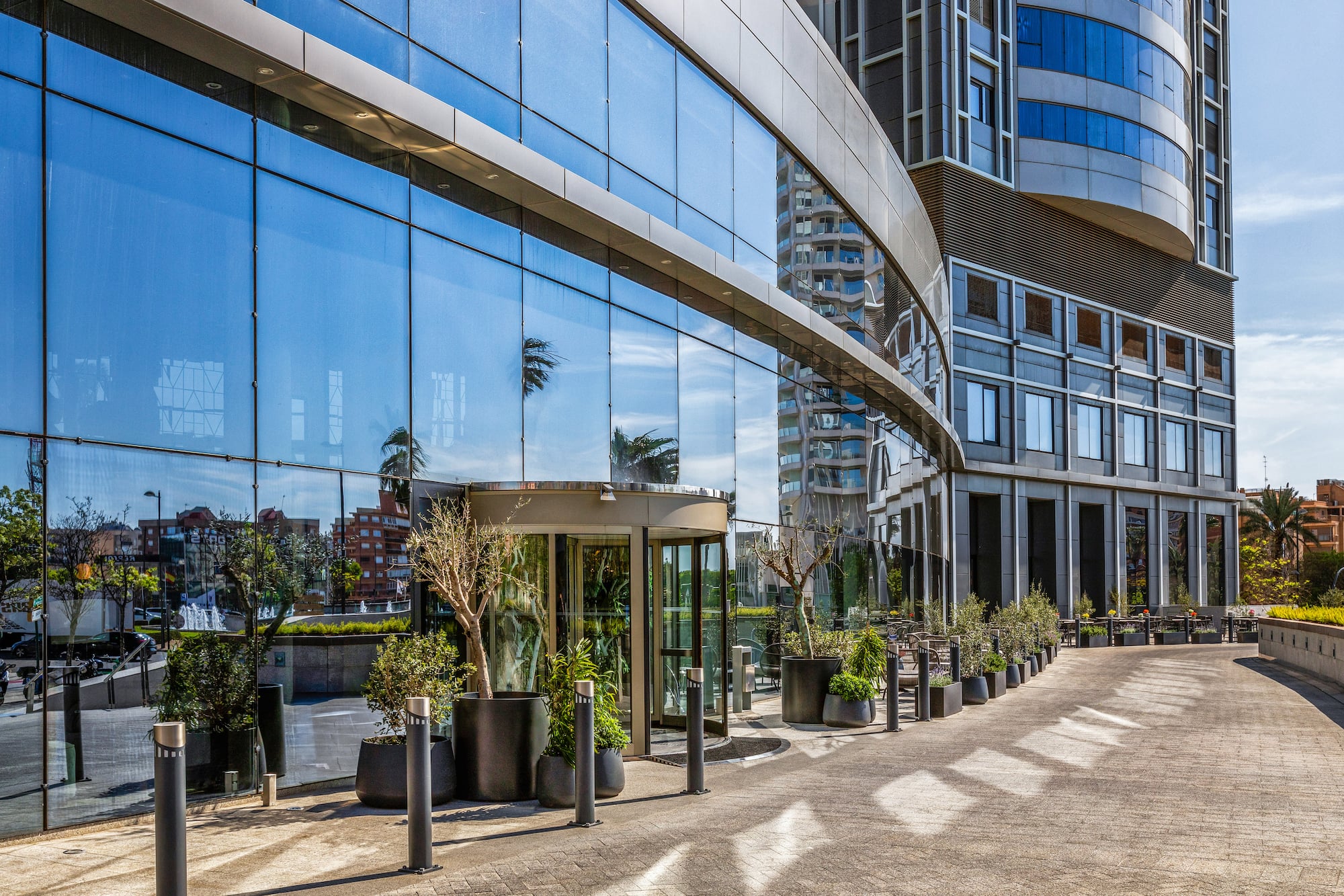 Modern glass office building with blue reflective facade and revolving door.