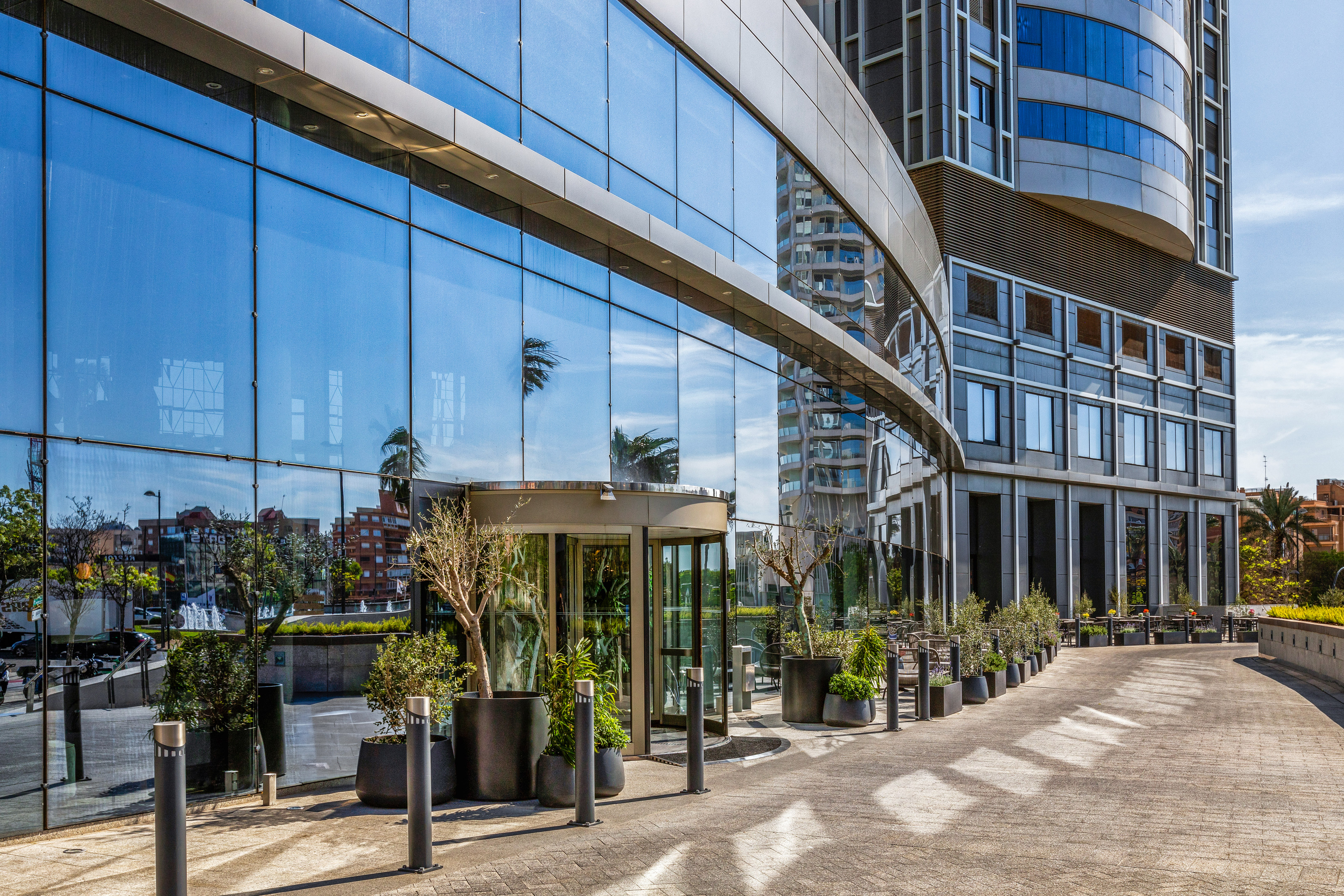 Modern glass office building with blue reflective facade and revolving door.