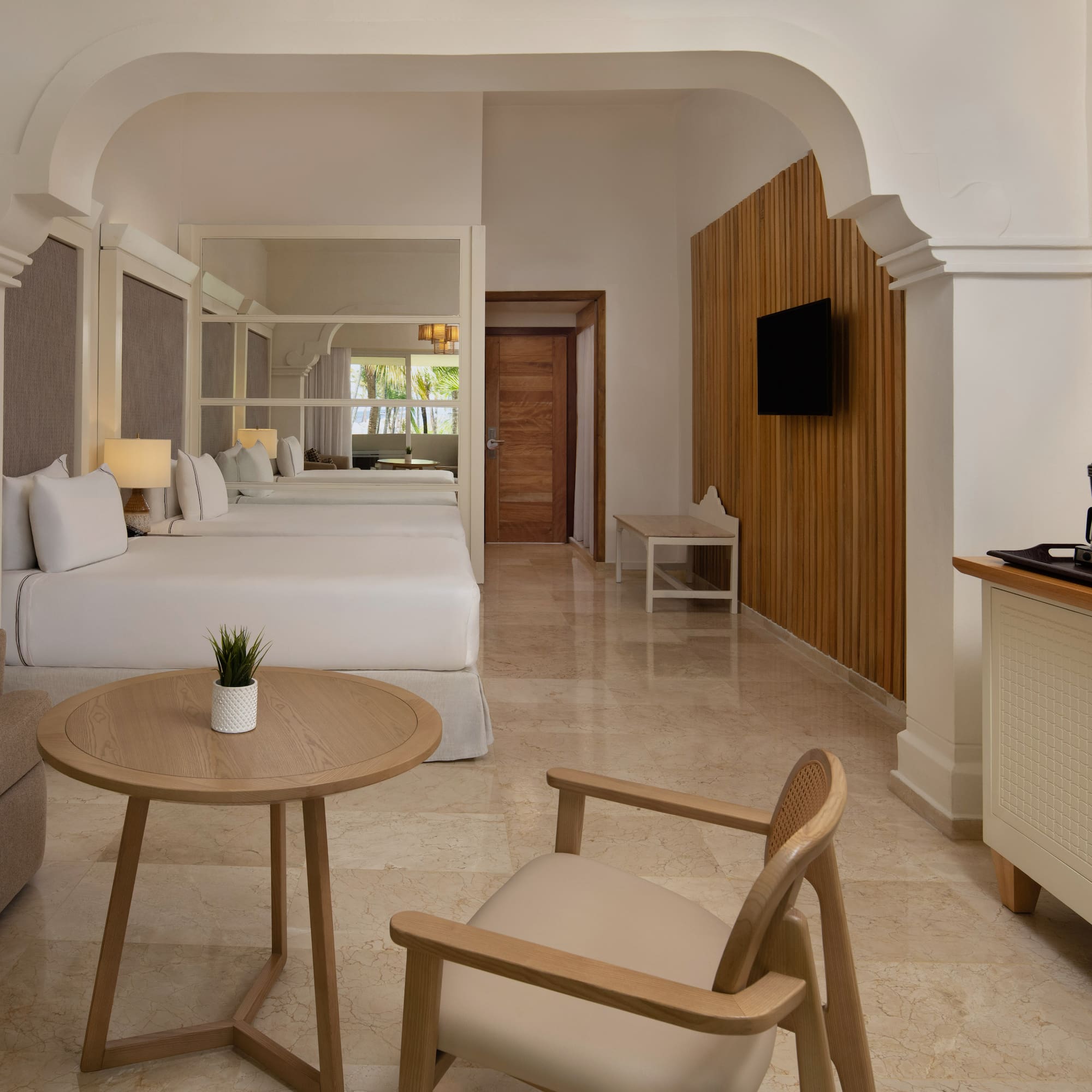 Luxurious hotel room with two beds, sofa, coffee maker, and modern design.