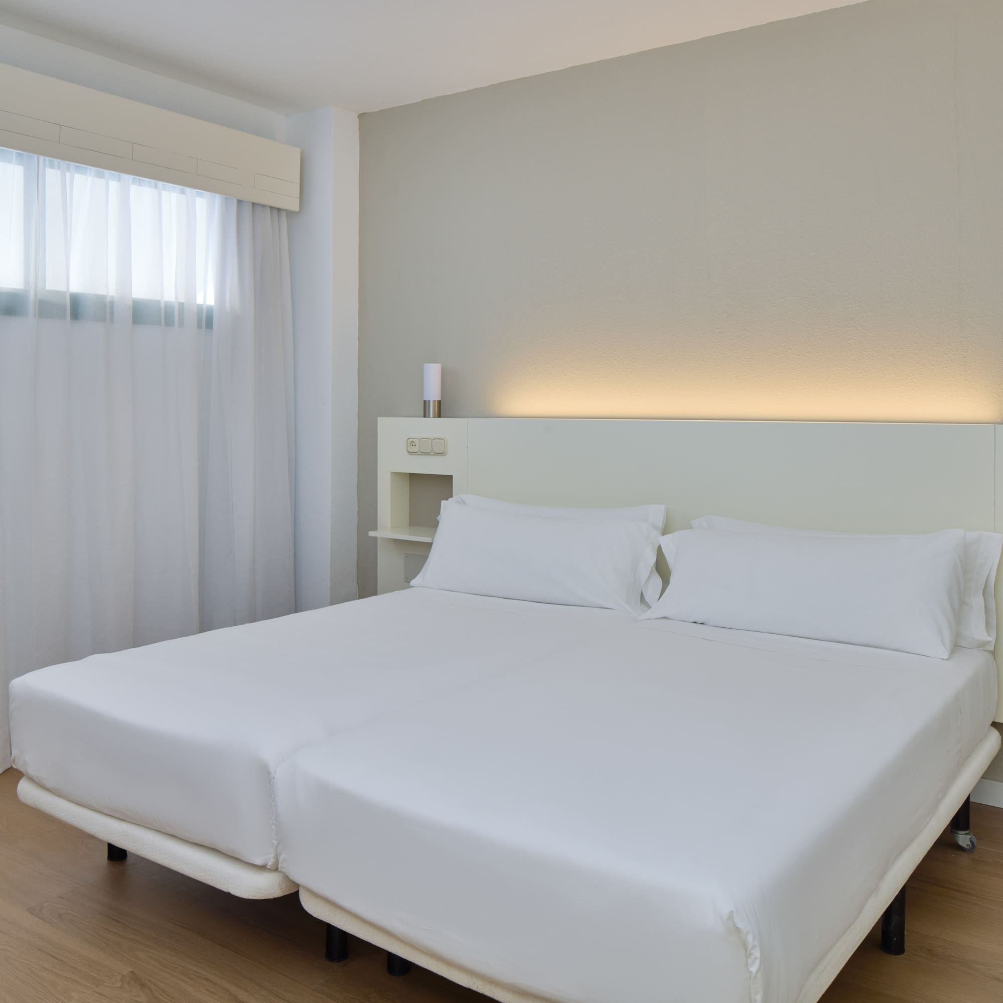 a bed with white sheets and a wood floor