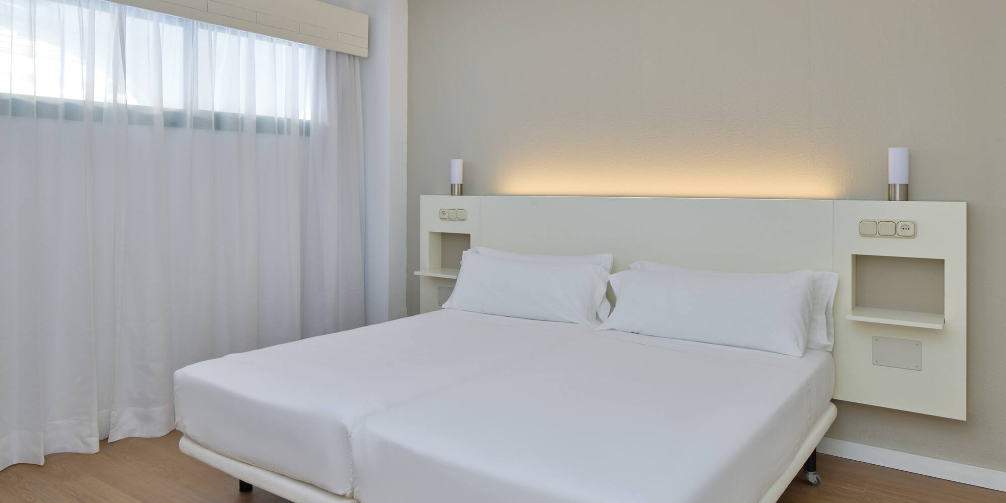 a bed with white sheets and a wood floor