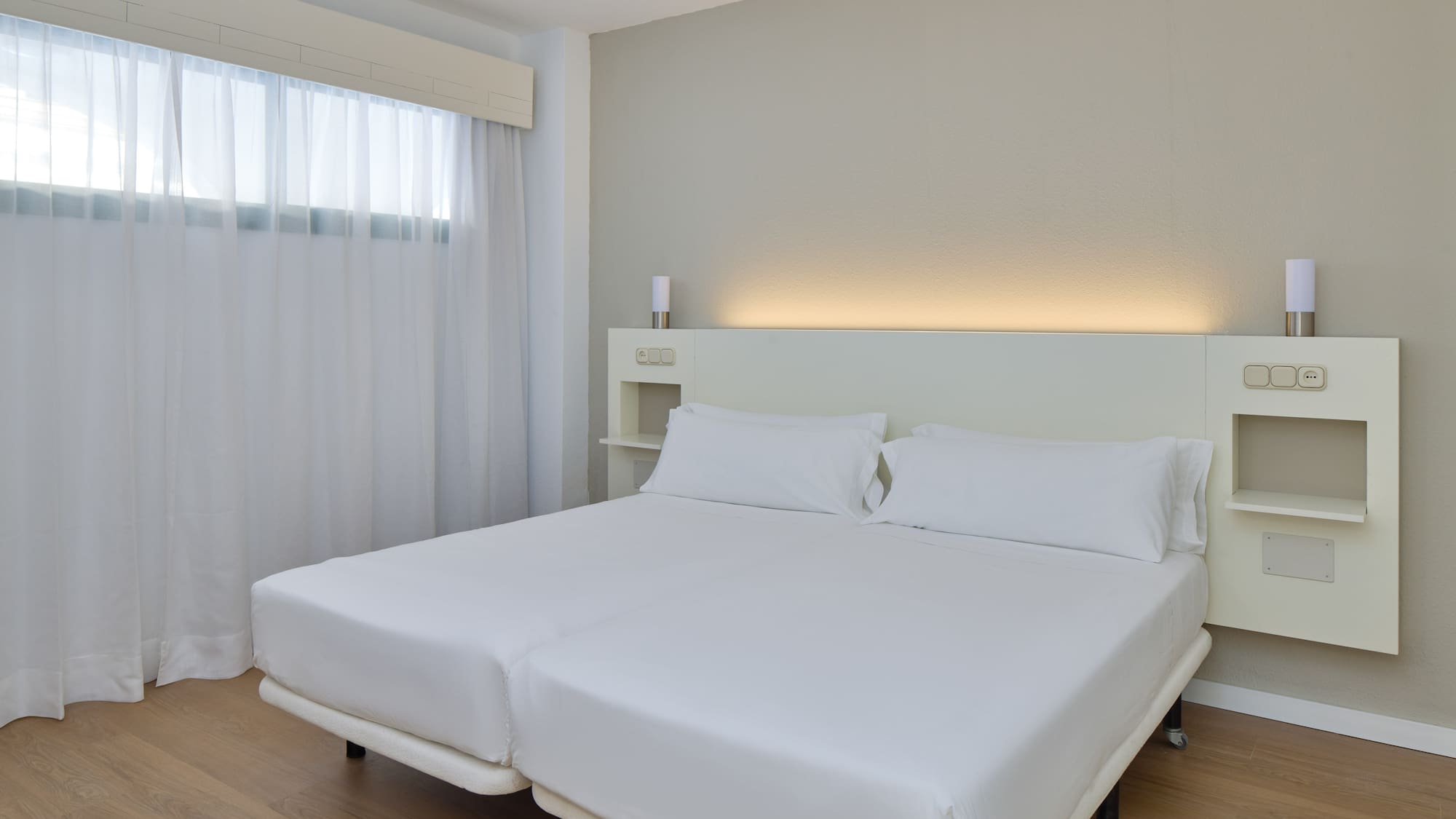 a bed with white sheets and a wood floor
