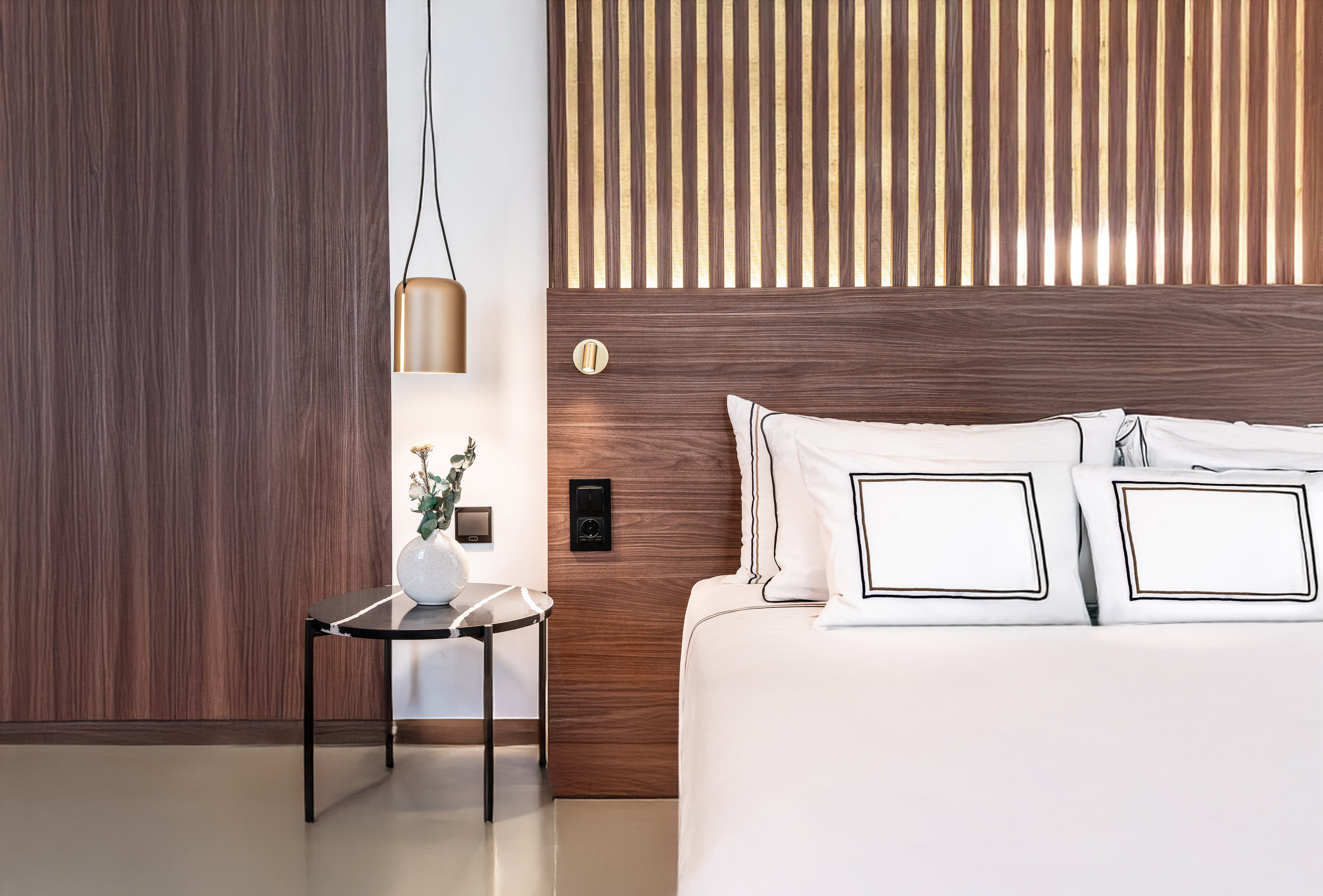 a bed with white pillows and a vase of flowers on a table