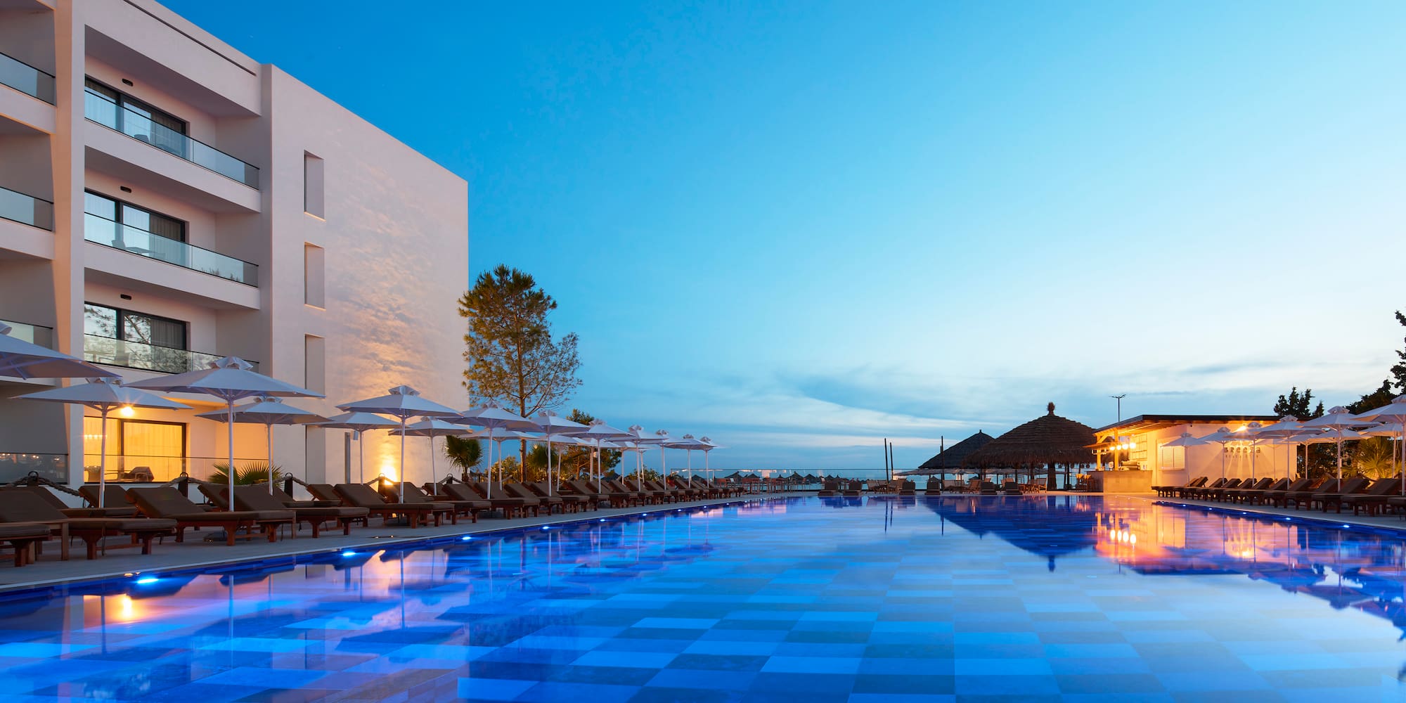 a pool with umbrellas and chairs in front of a building