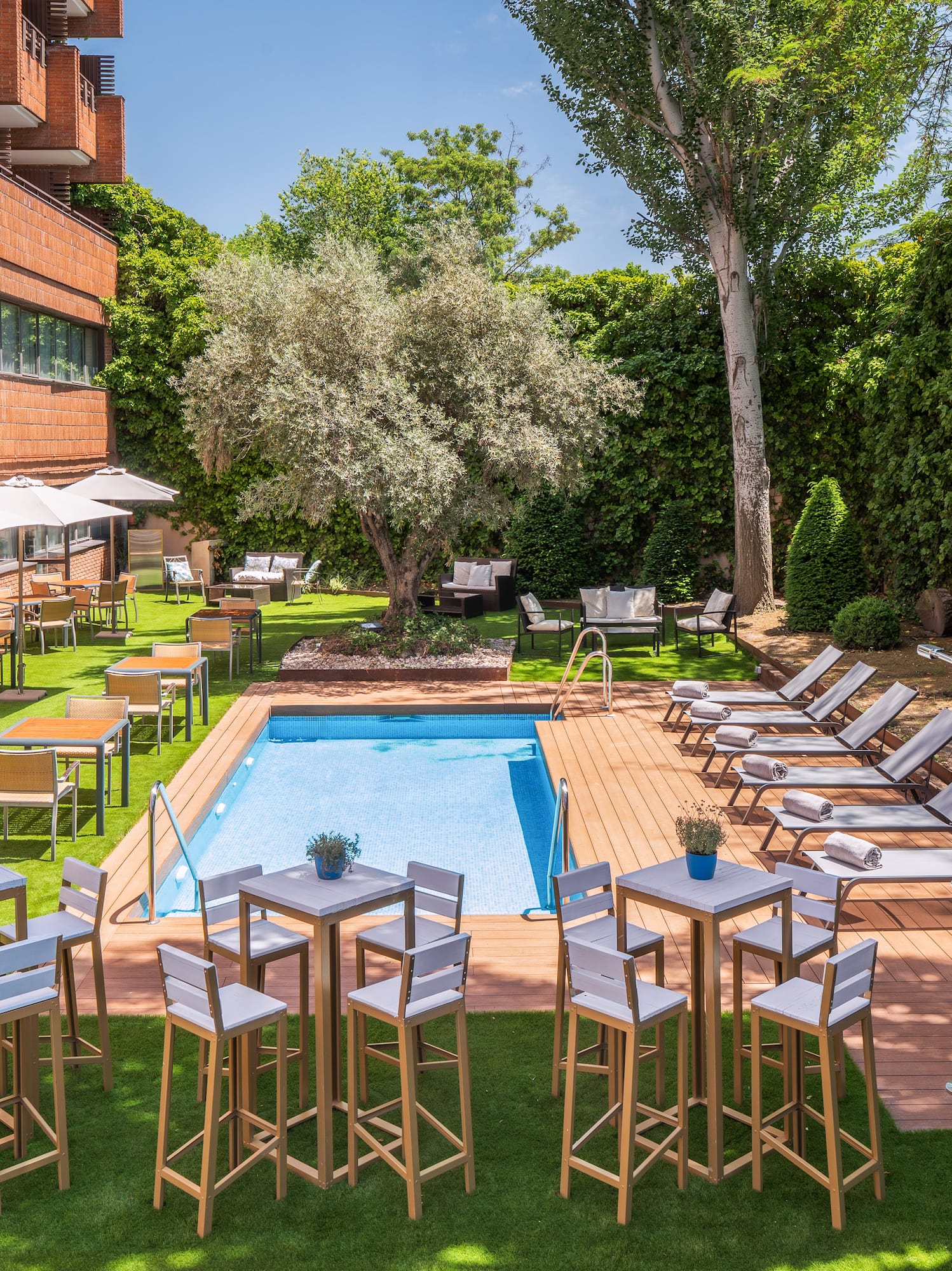 a pool with chairs and tables in a courtyard